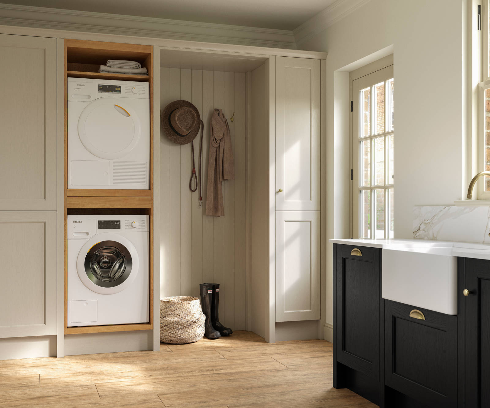 Utility room with Traditional Shaker-style tactile woodgrain Ludlow French Clay cabinets, washing machine and tumble dryer, Ludlow Sumi Black kitchen with brass accessories, Amtico oak stripwood vinyl flooring.