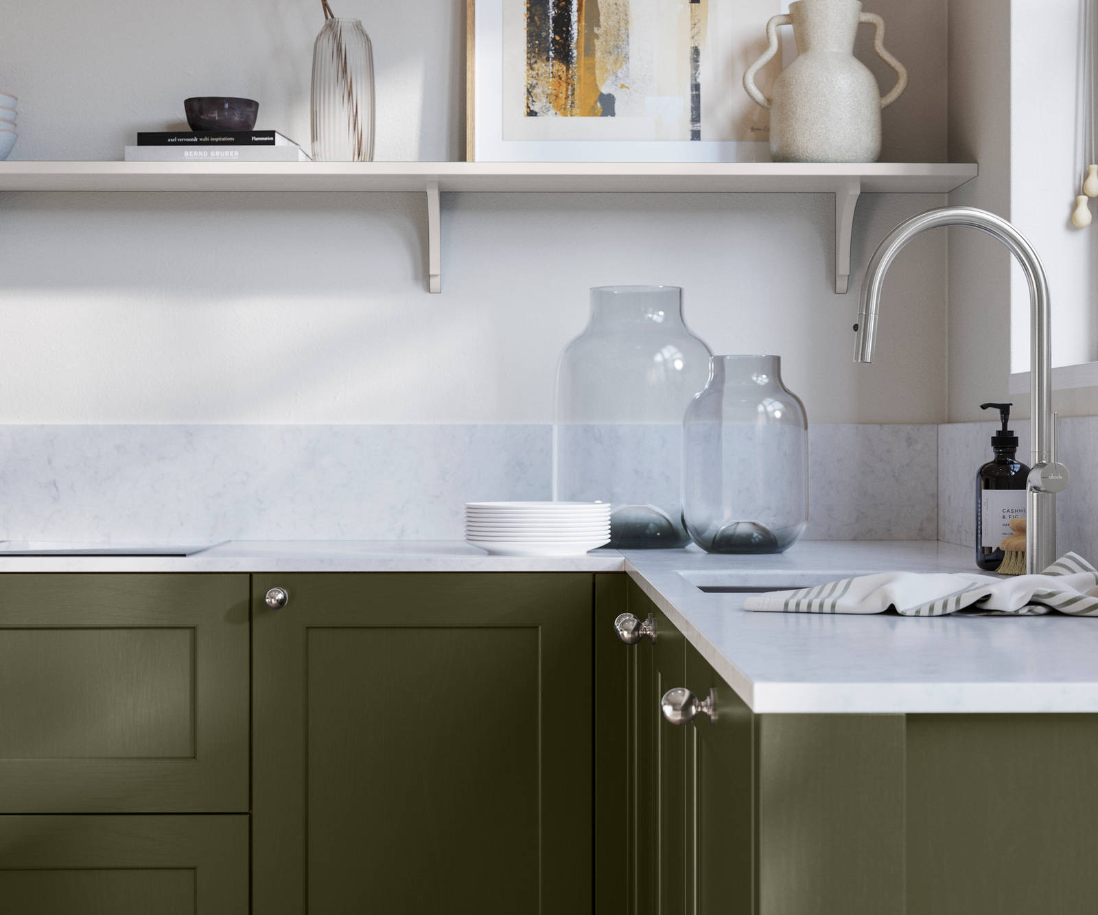 Ludlow, a traditional Shaker-style premium feel kitchen range with a visible woodgrain on its panelled doors here shown in the shade Tailored Green styled with steel knobs, steel tap, a white marbled worktop with matching splashback.