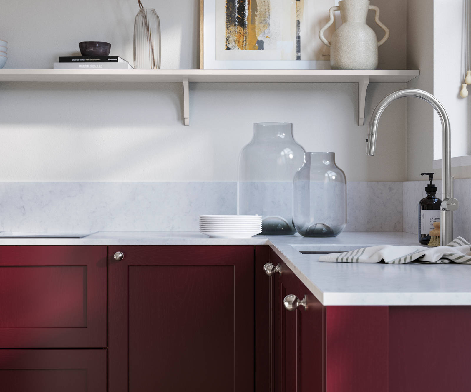 Wardley Morello kitchen cabinetry with steel knobs, steel tap, white marbled worktop and matching backsplash. An open shelf on the wall above cabinets with ceramics and a vase of flowers.