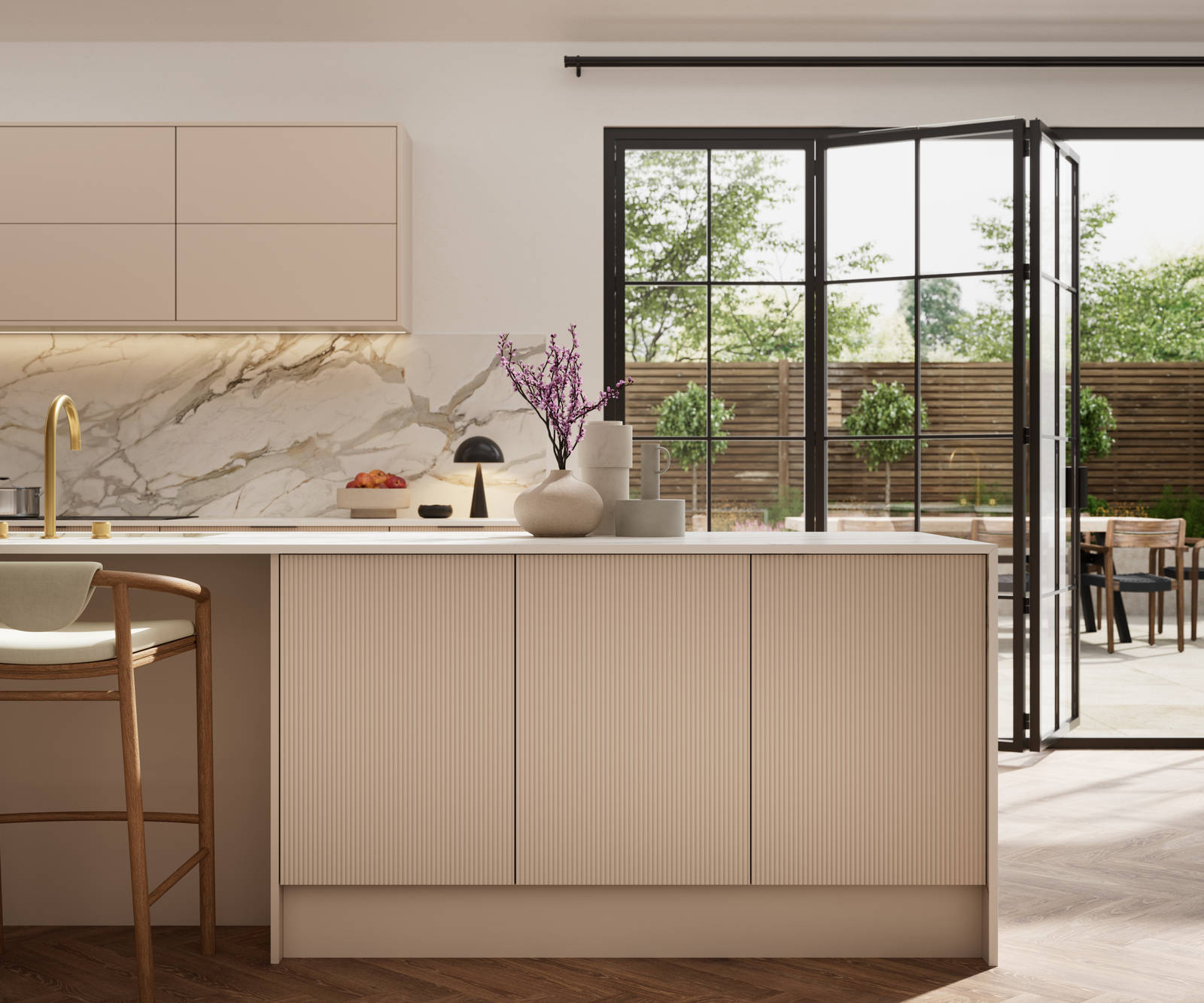 Fluted front kitchen Reed from Magnet in light warm neutral shade Shell, with a marbled splashback, worktop and decorative side on kitchen island with barstools and black handles, herringbone wood flooring.