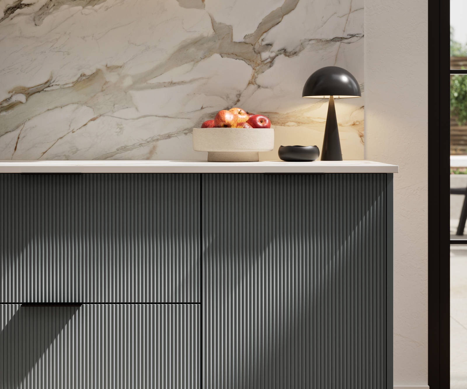 Fluted front kitchen Reed from Magnet in dark green shade Arboretum, with a marbled splashback and black handles, herringbone wood flooring.
