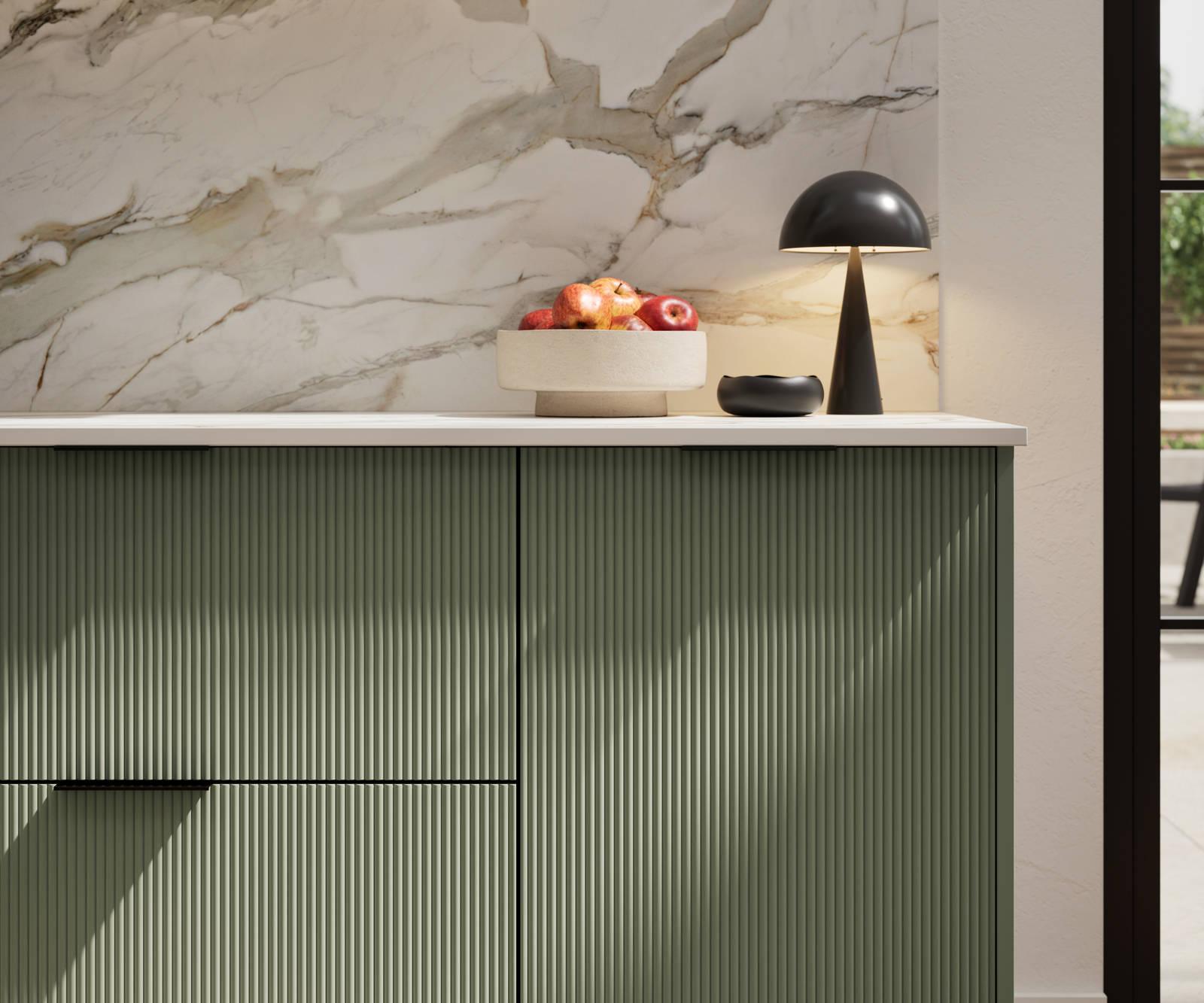 Fluted front kitchen Reed from Magnet in rich dark green shade Thyme, with a marbled splashback and black handles, herringbone wood flooring.