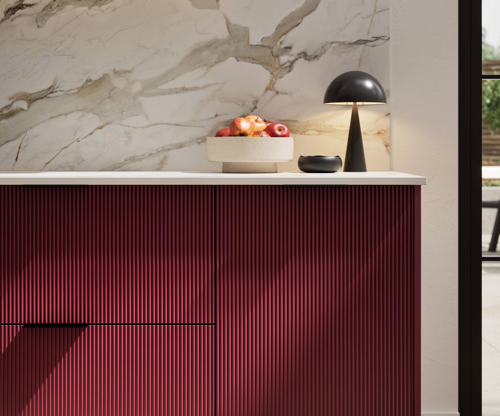 Fluted front kitchen Reed from Magnet in red shade Morello, with a marbled splashback and black handles, herringbone wood flooring.