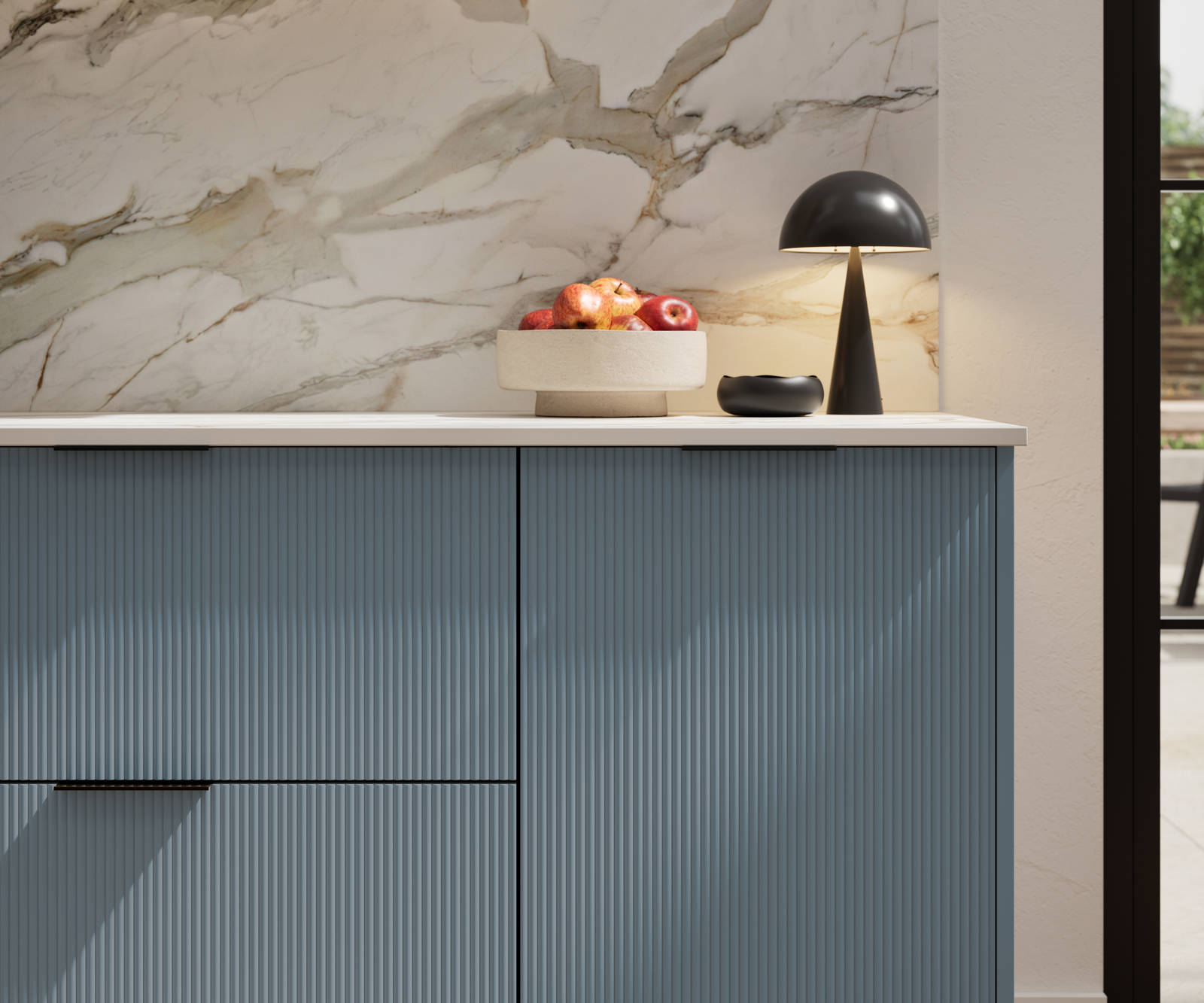 Fluted front kitchen Reed from Magnet in bright blue shade Portland Blue, with a marbled splashback and black handles, herringbone wood flooring.