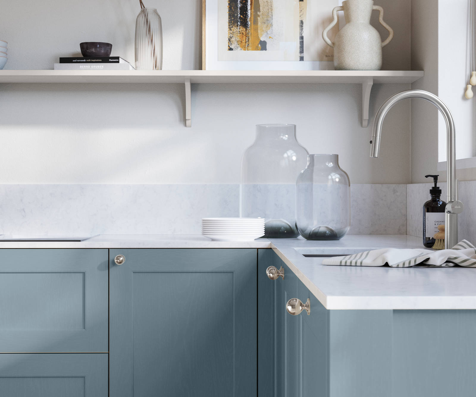 Ludlow, a traditional Shaker-style premium feel kitchen range with a visible woodgrain on its panelled doors here shown in the shade Portland Blue styled with steel knobs, steel tap, a white marbled worktop with matching splashback.