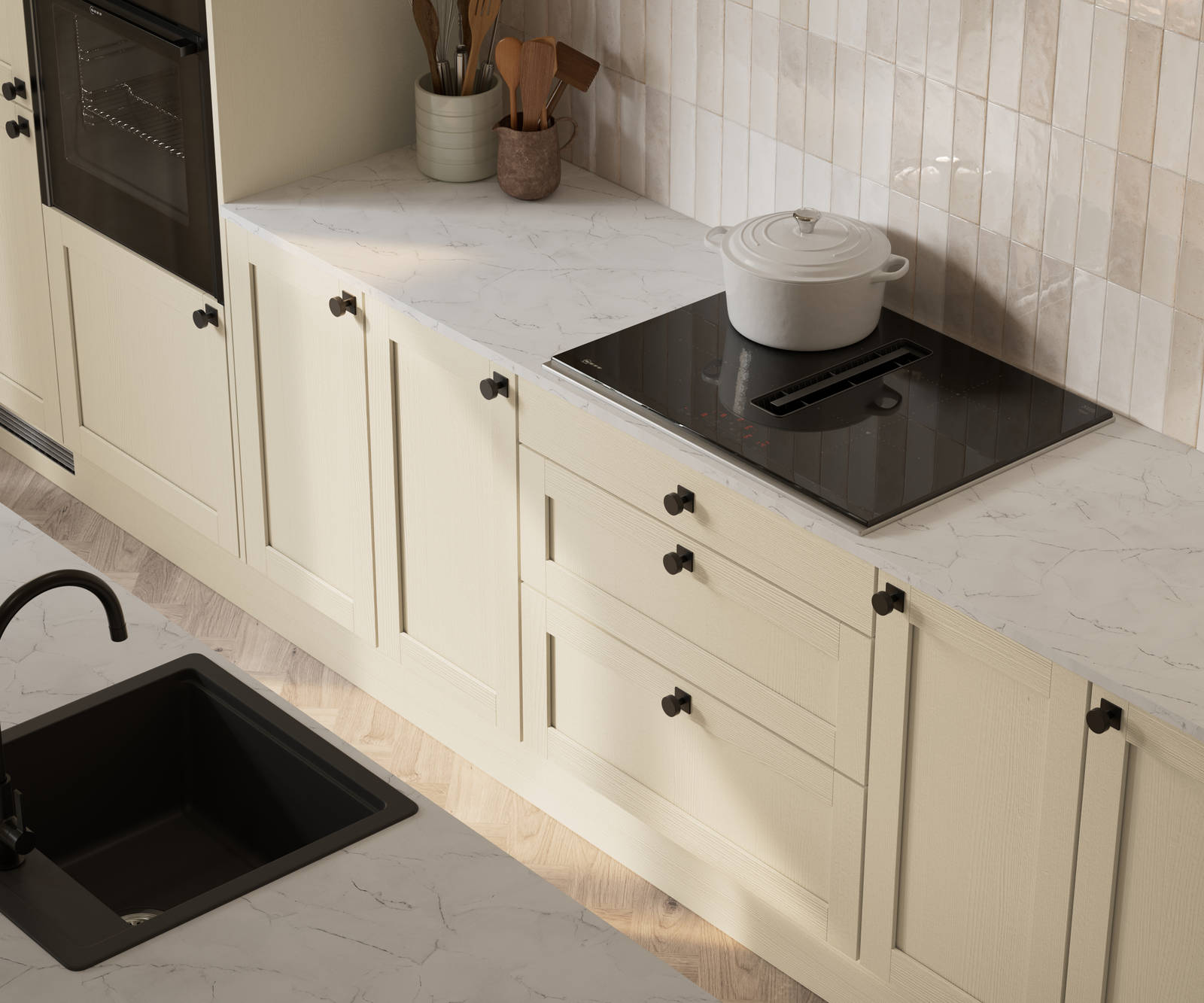View from above of contemporary Shaker kitchen Ambleside from Magnet in neutral shade Sand with black sink and tap in kitchen island, induction hob with extractor, marbled worktop and black knobs.