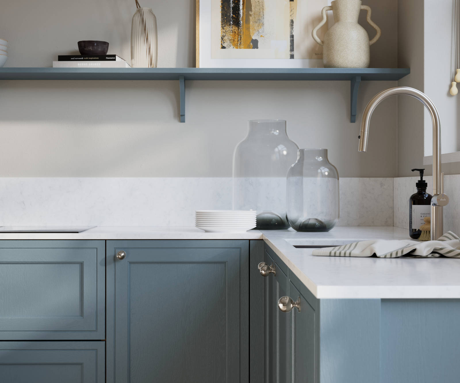 Bewdley Portland Blue painted wood grain Shaker kitchen cabinetry with steel knobs, steel tap, white marbled worktop and matching backsplash, an open shelf on the wall above cabinets with ceramics and a vase of flowers.