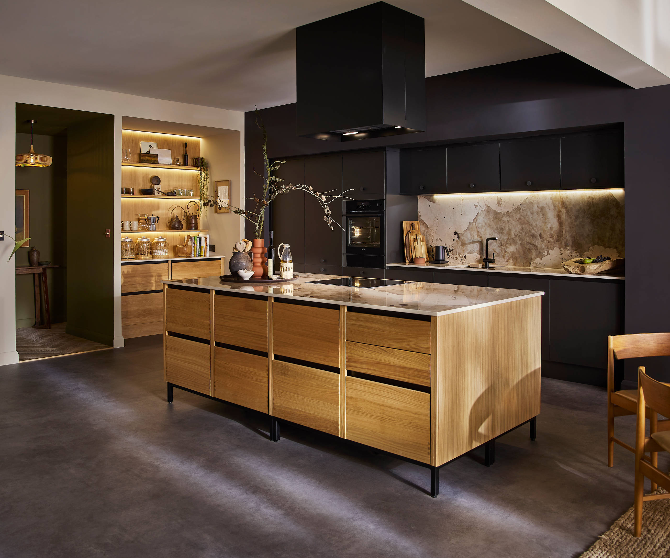 View of natural oak Nordic Craft kitchen island contrasting against the dark Sumi Black Hoxton cabinetry behind it.