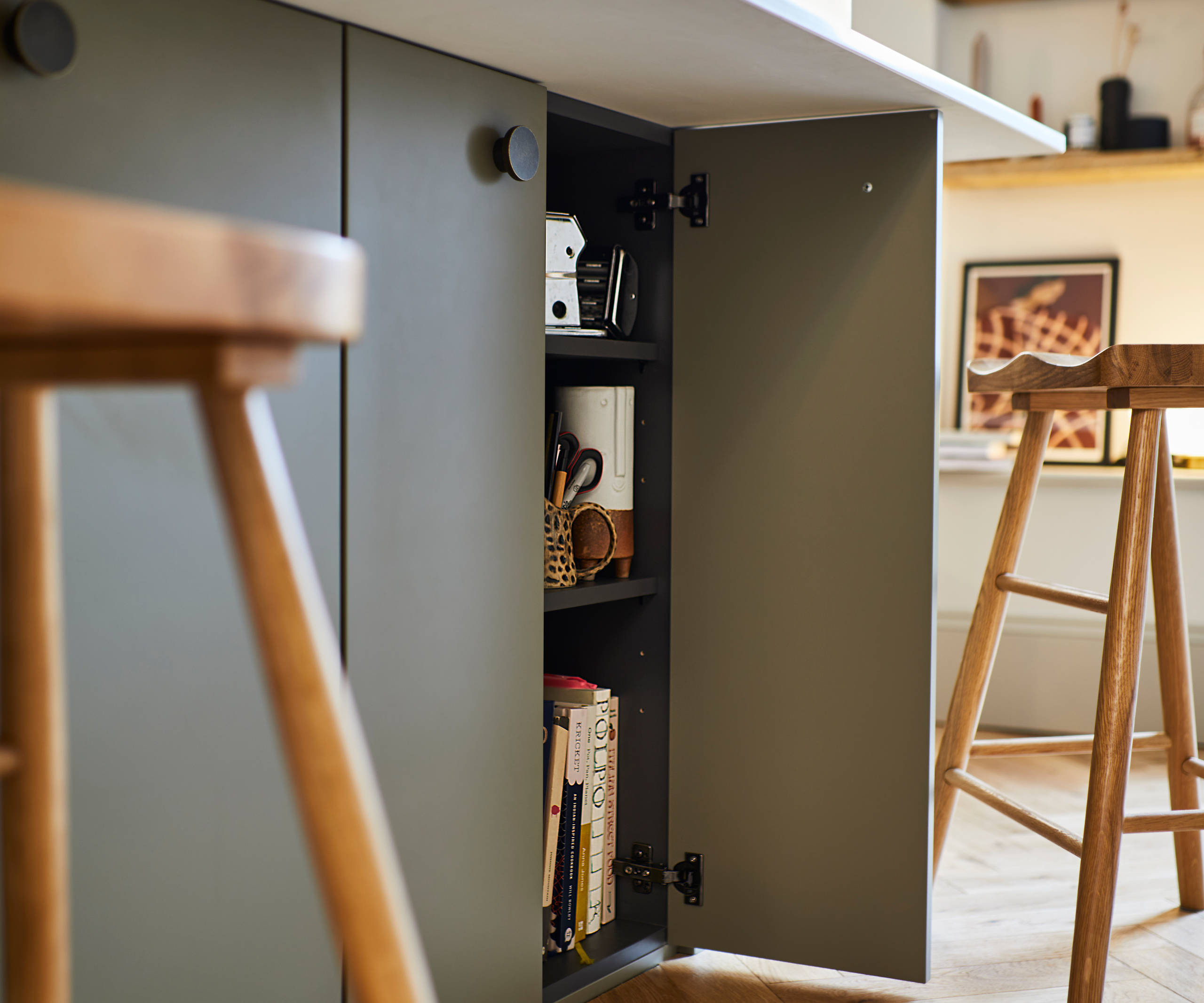Close-up of opened cabinet in Soho Balmoral kitchen island, with light wood barstools