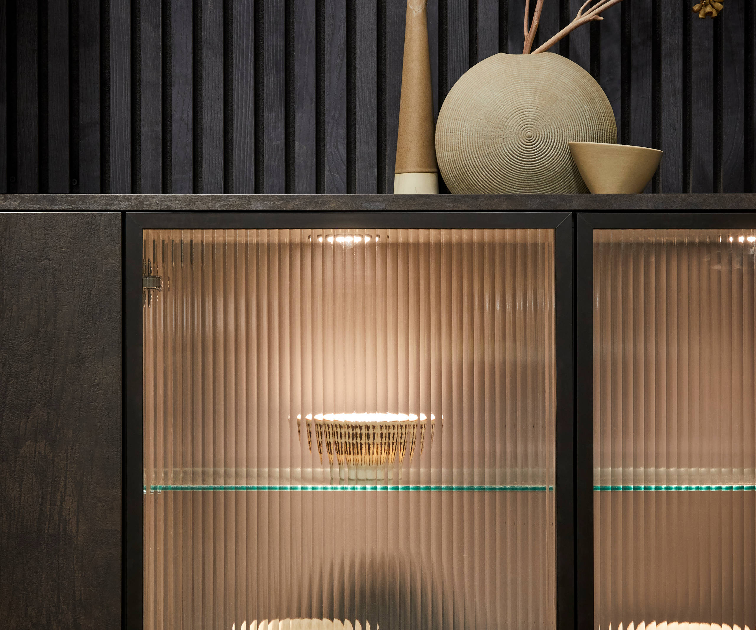 Elegant fluted glass cabinets, shown with contemporary dark wood panelling and modern Portobello kitchen cabinets in Etna.