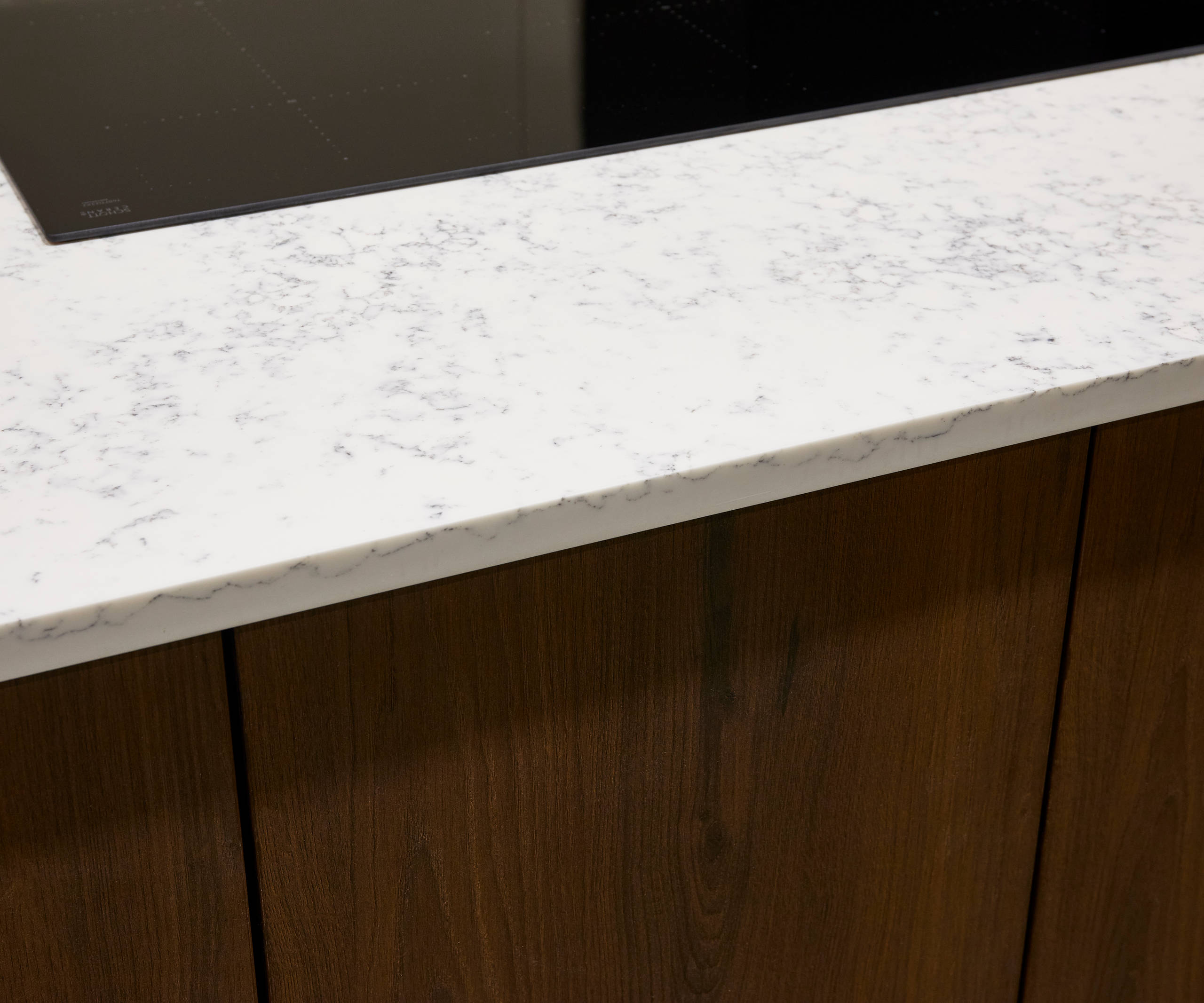 Wooden kitchen cabinets paired with white marble-effect worktop and modern glass hob.