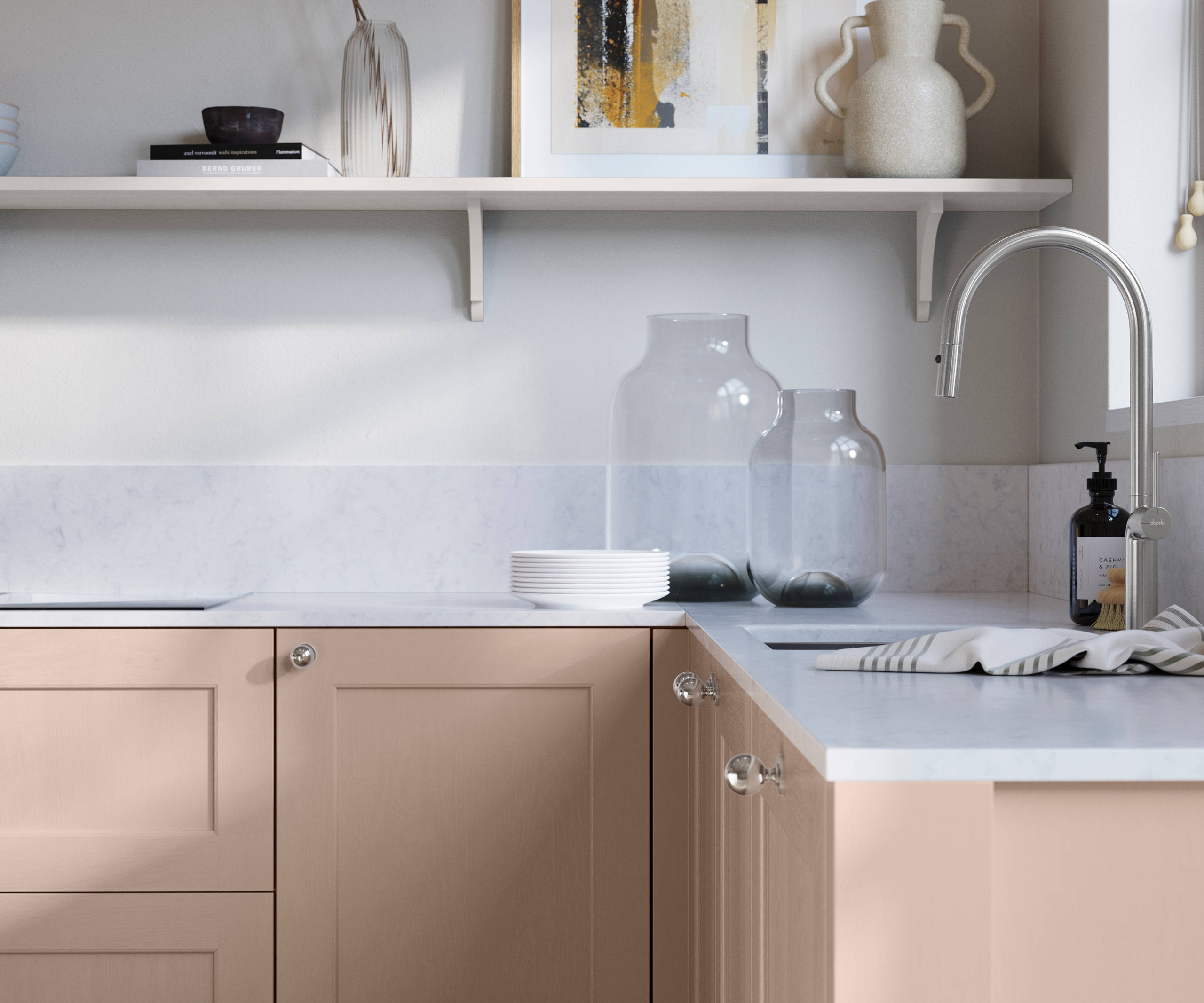 Ludlow, a traditional Shaker-style premium feel kitchen range with a visible woodgrain on its panelled doors here shown in the light pink shade Chalk Blush styled with steel knobs, steel tap, a white marbled worktop with matching splashback.