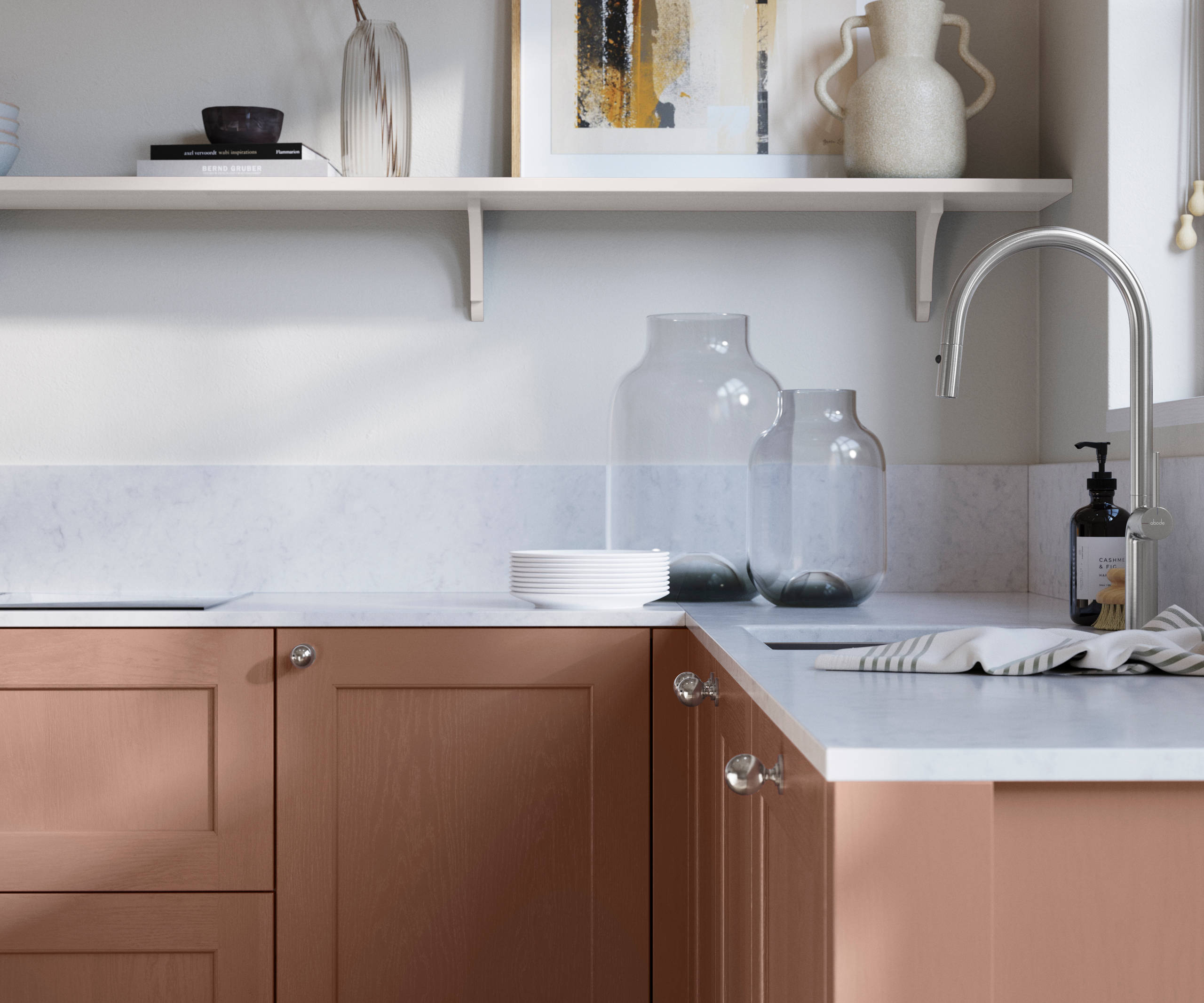 Ludlow, a traditional Shaker-style premium feel kitchen range with a visible woodgrain on its panelled doors here shown in the shade Clay styled with steel knobs, steel tap, a white marbled worktop with matching splashback.