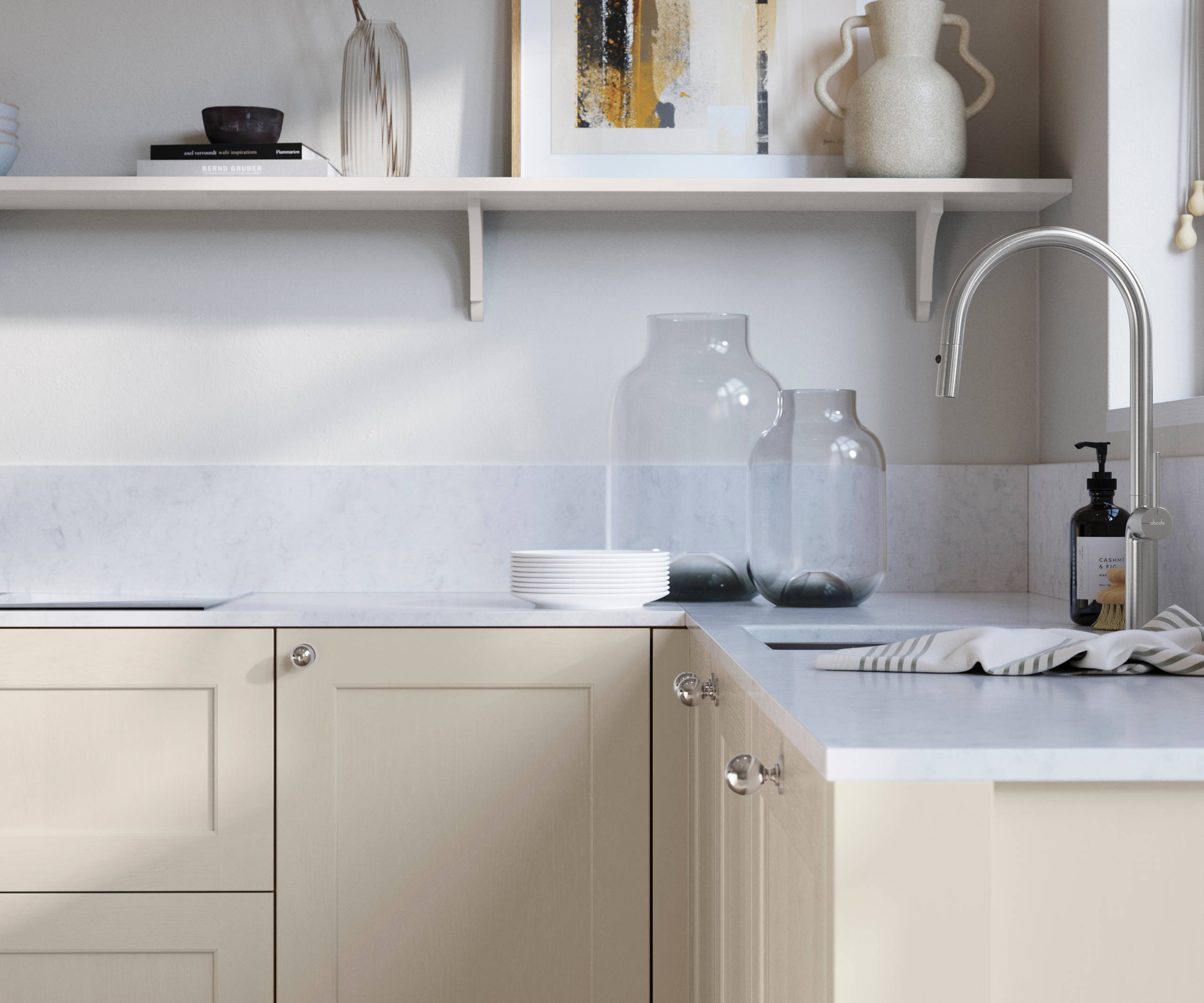 Ludlow, a traditional Shaker-style premium feel kitchen range with a visible woodgrain on its panelled doors here shown in the light shade limestone styled with steel knobs, steel tap, a white marbled worktop with matching splashback.