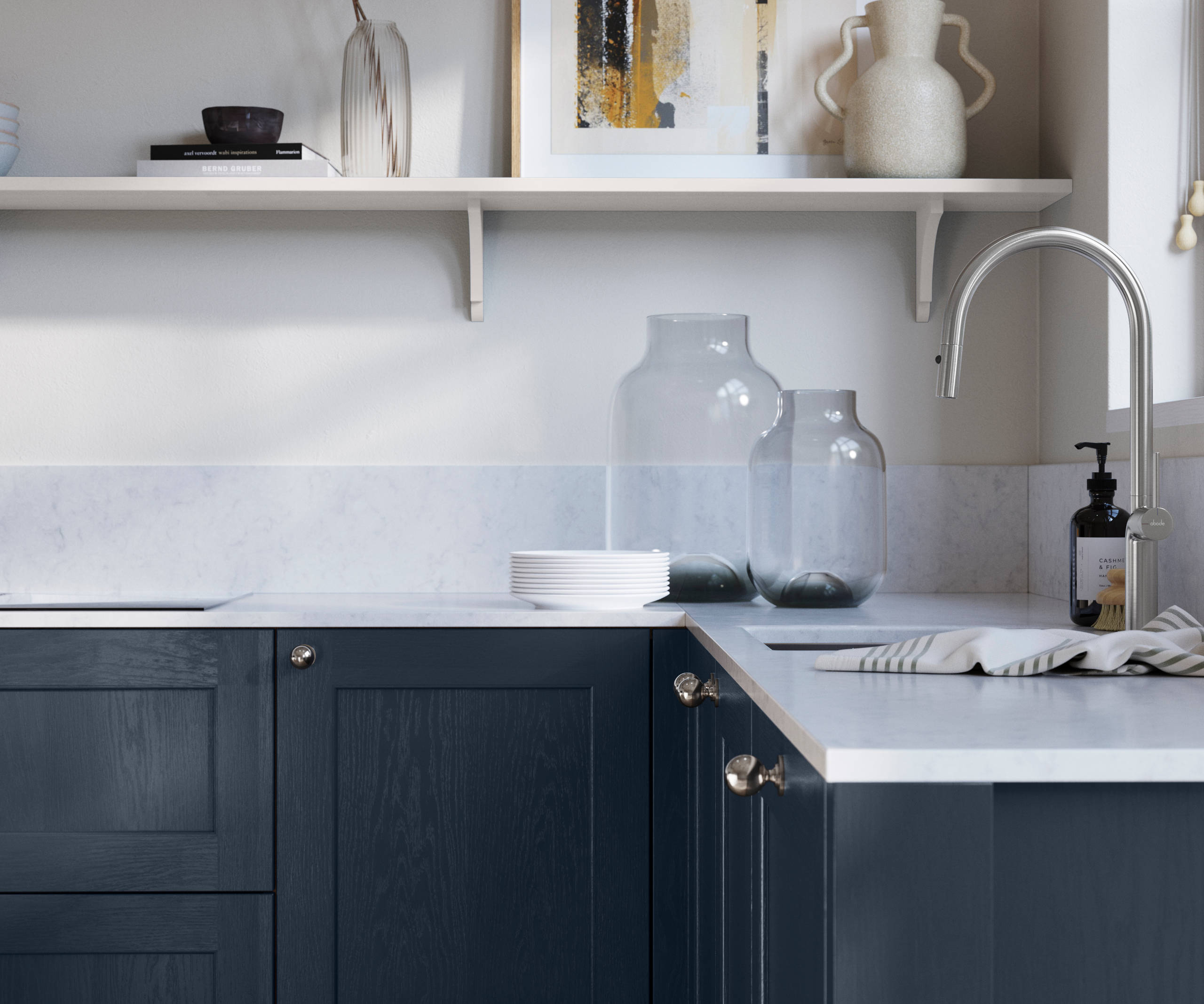 Ludlow, a traditional Shaker-style premium feel kitchen range with a visible woodgrain on its panelled doors here shown in the dark blue shade Midnight styled with steel knobs, steel tap, a white marbled worktop with matching splashback.