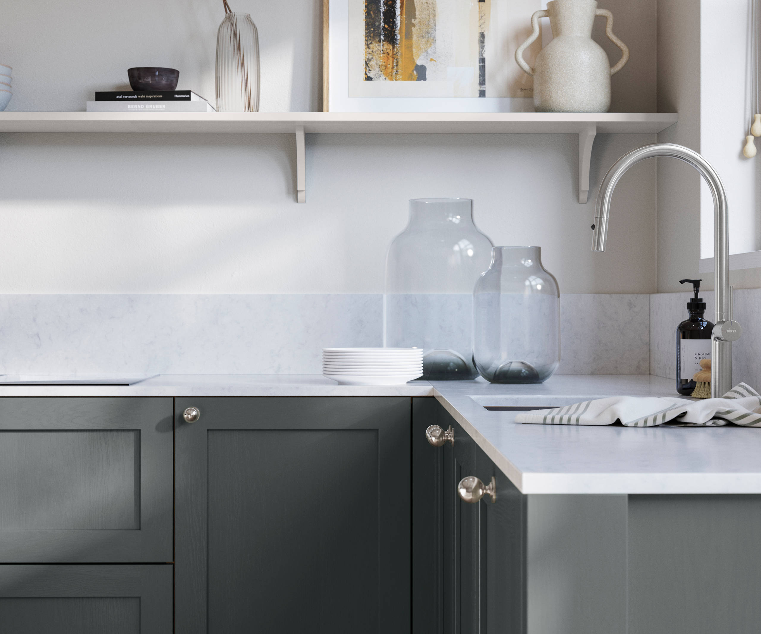 Wardley Arboretum kitchen cabinetry with steel knobs, steel tap, white marbled worktop and matching backsplash. An open shelf on the wall above cabinets with ceramics and a vase of flowers.