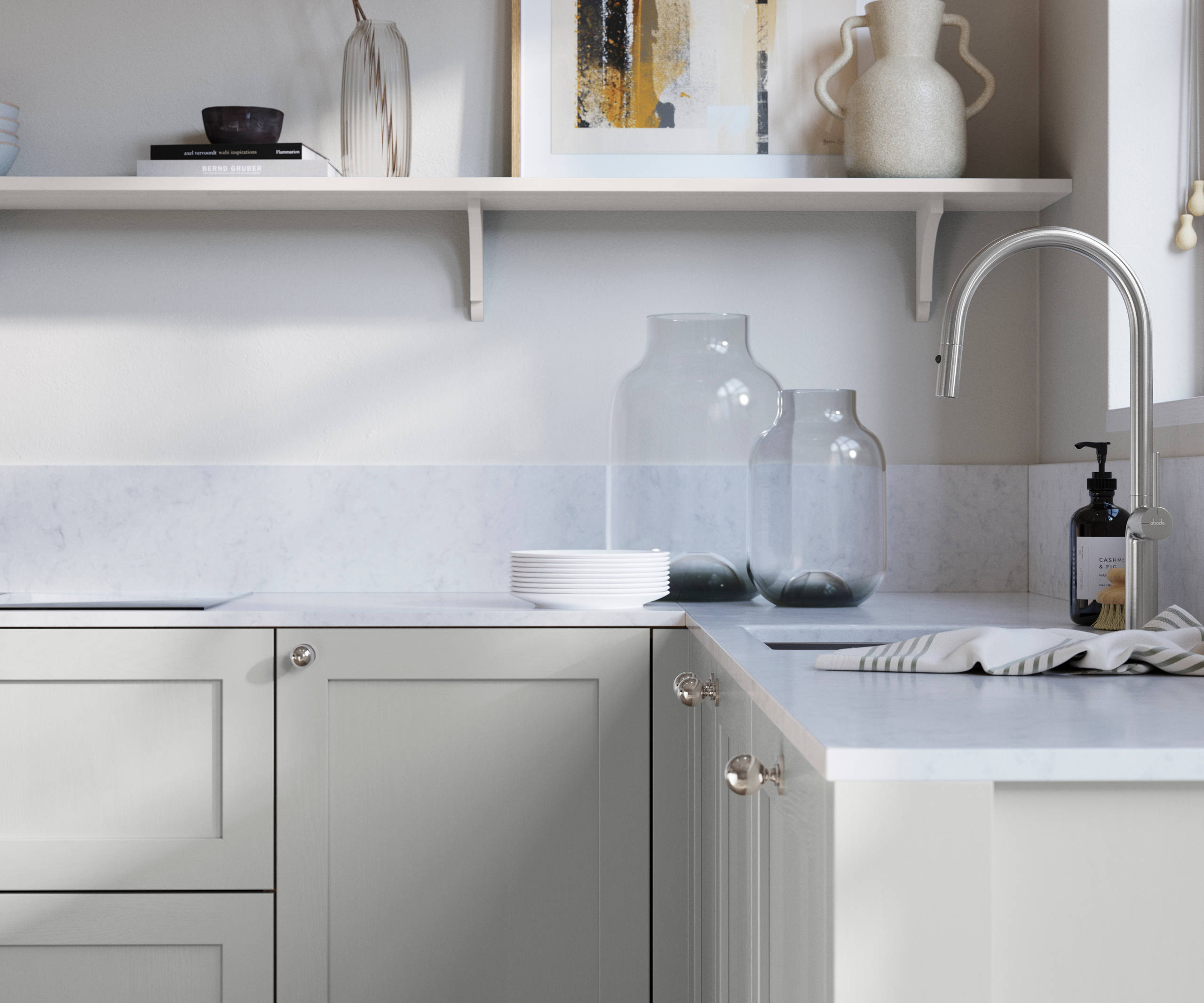 Wardley Washed Cotton kitchen cabinetry with steel knobs, steel tap, white marbled worktop and matching backsplash. An open shelf on the wall above cabinets with ceramics and a vase of flowers.