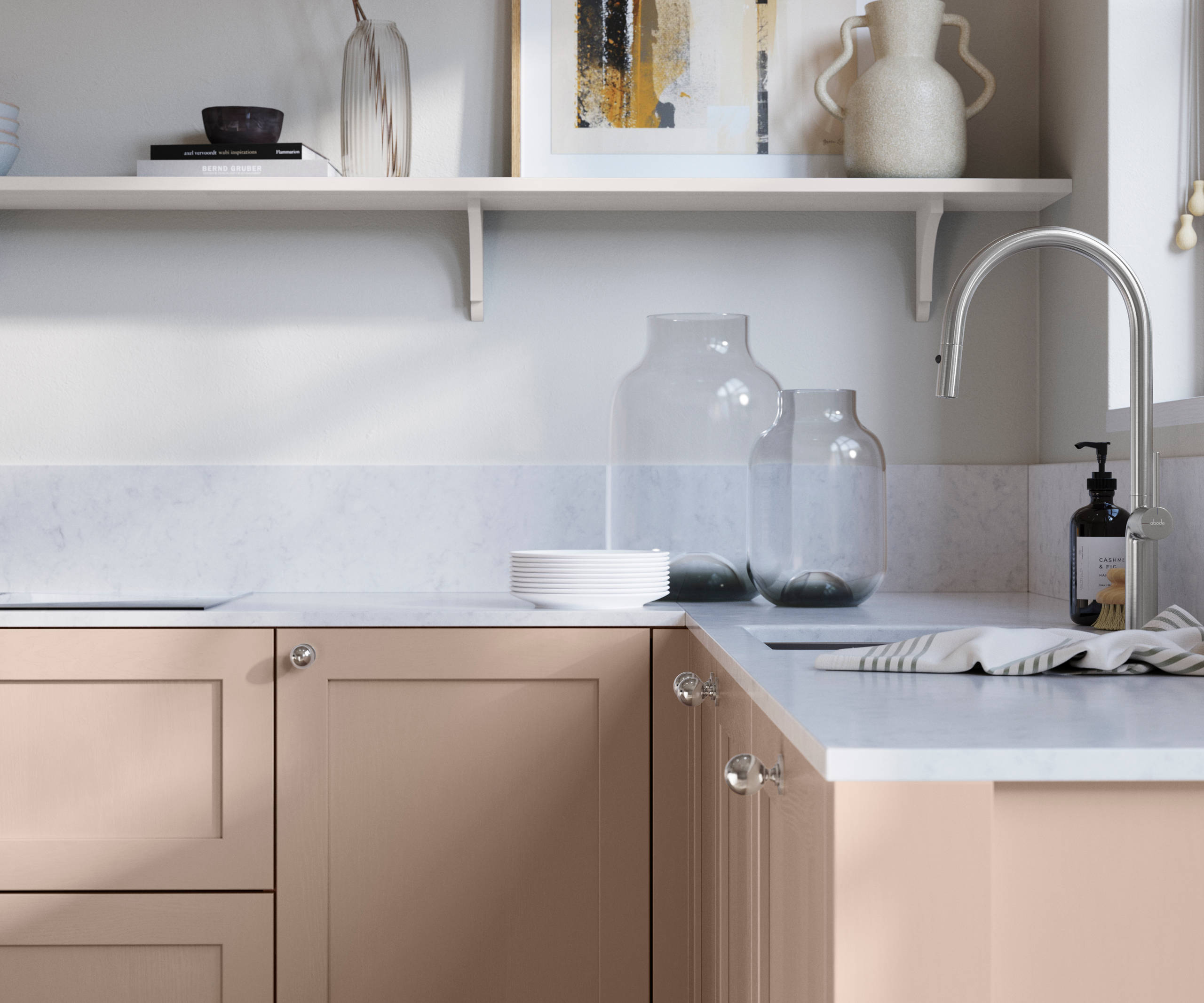 Wardley Chalk Blush kitchen cabinetry with steel knobs, steel tap, white marbled worktop and matching backsplash. An open shelf on the wall above cabinets with ceramics and a vase of flowers.