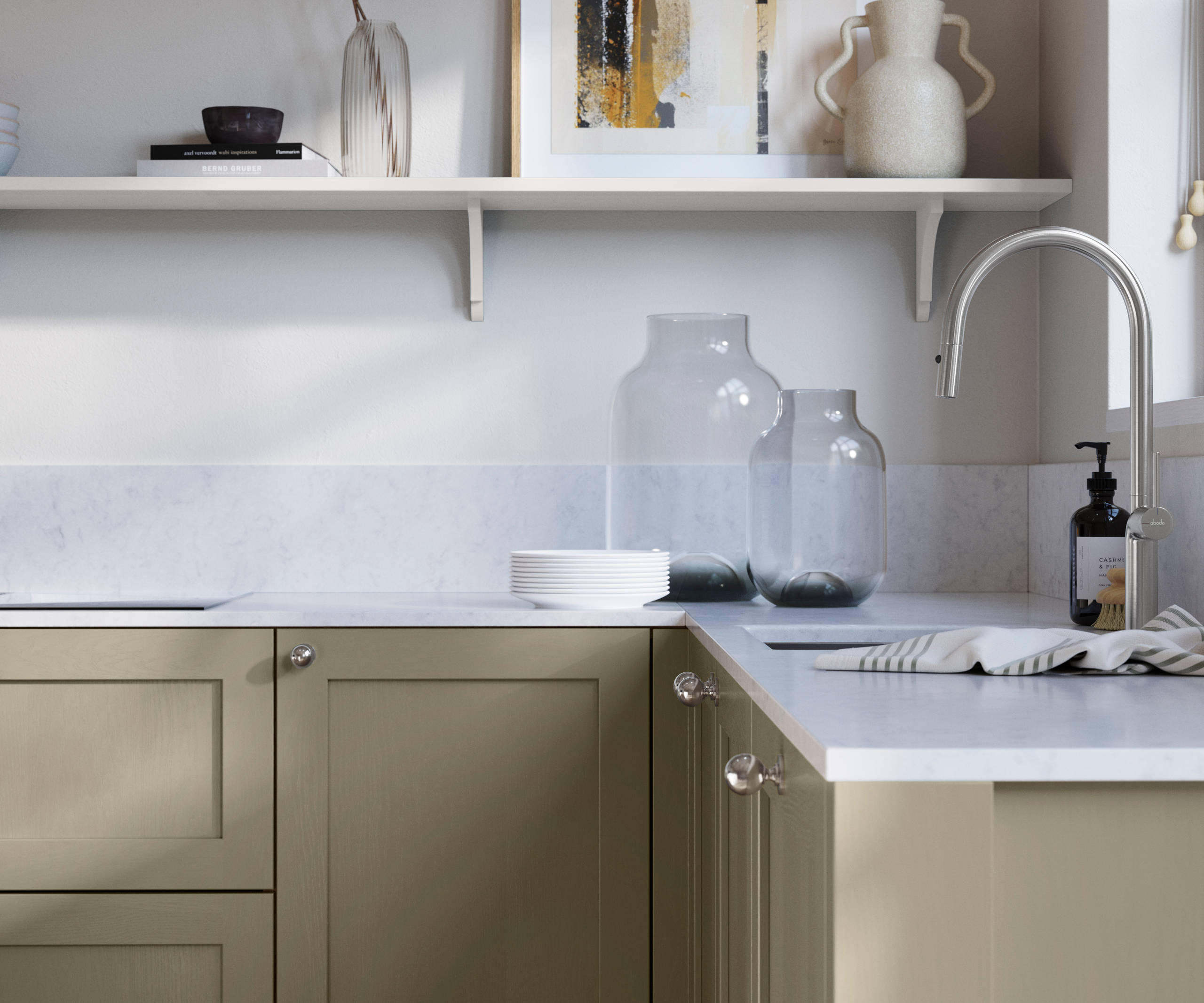 Wardley French clay kitchen cabinetry with steel knobs, steel tap, white marbled worktop and matching backsplash. An open shelf on the wall above cabinets with ceramics and a vase of flowers.