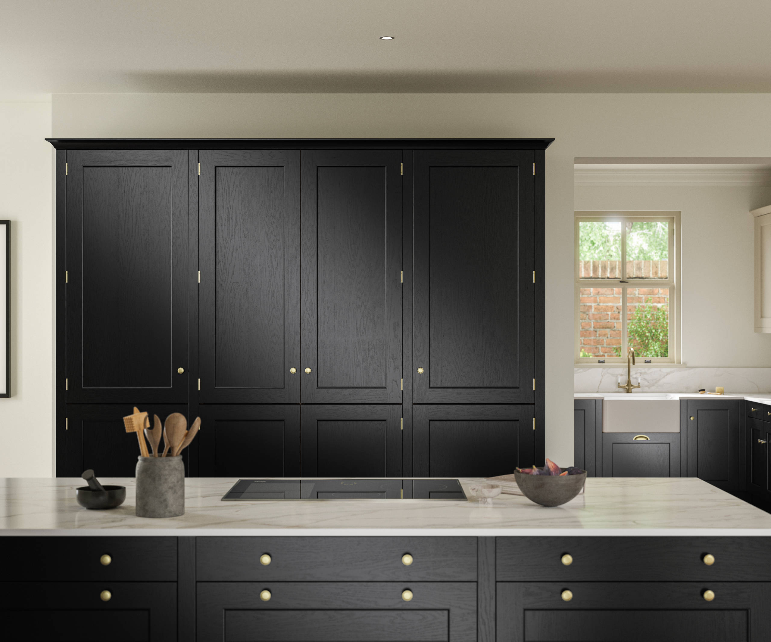 View over kitchen island in Traditional Shaker-style tactile woodgrain Ludlow Sumi Black kitchen with tall cabinets, brass accessories, marbled white and grey worktop, white ceramic sink and brass tap.