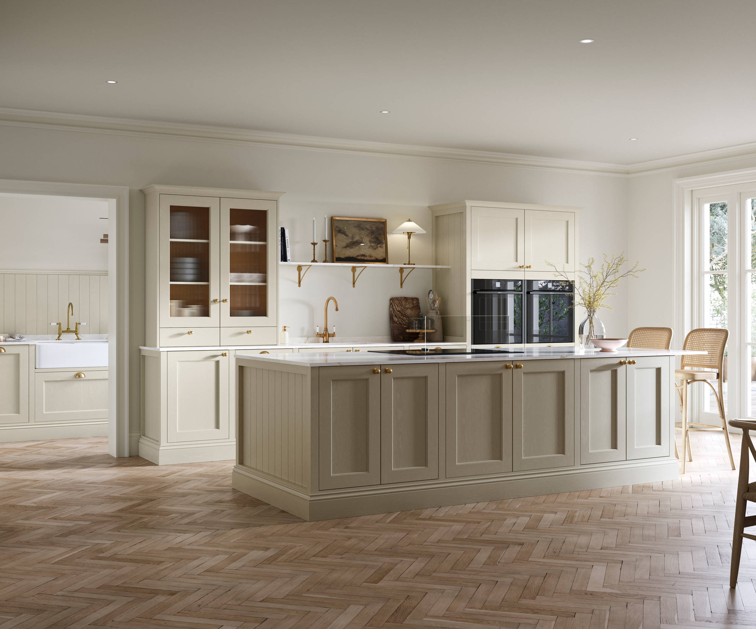 Open plan living room and Traditional Shaker-style kitchen Ludlow Parchment with tactile woodgrain, flute glass vitrine cabinets,  brass acessories like handles and tap, integrated ovens, a kitchen island and light wood herringbone flooring.