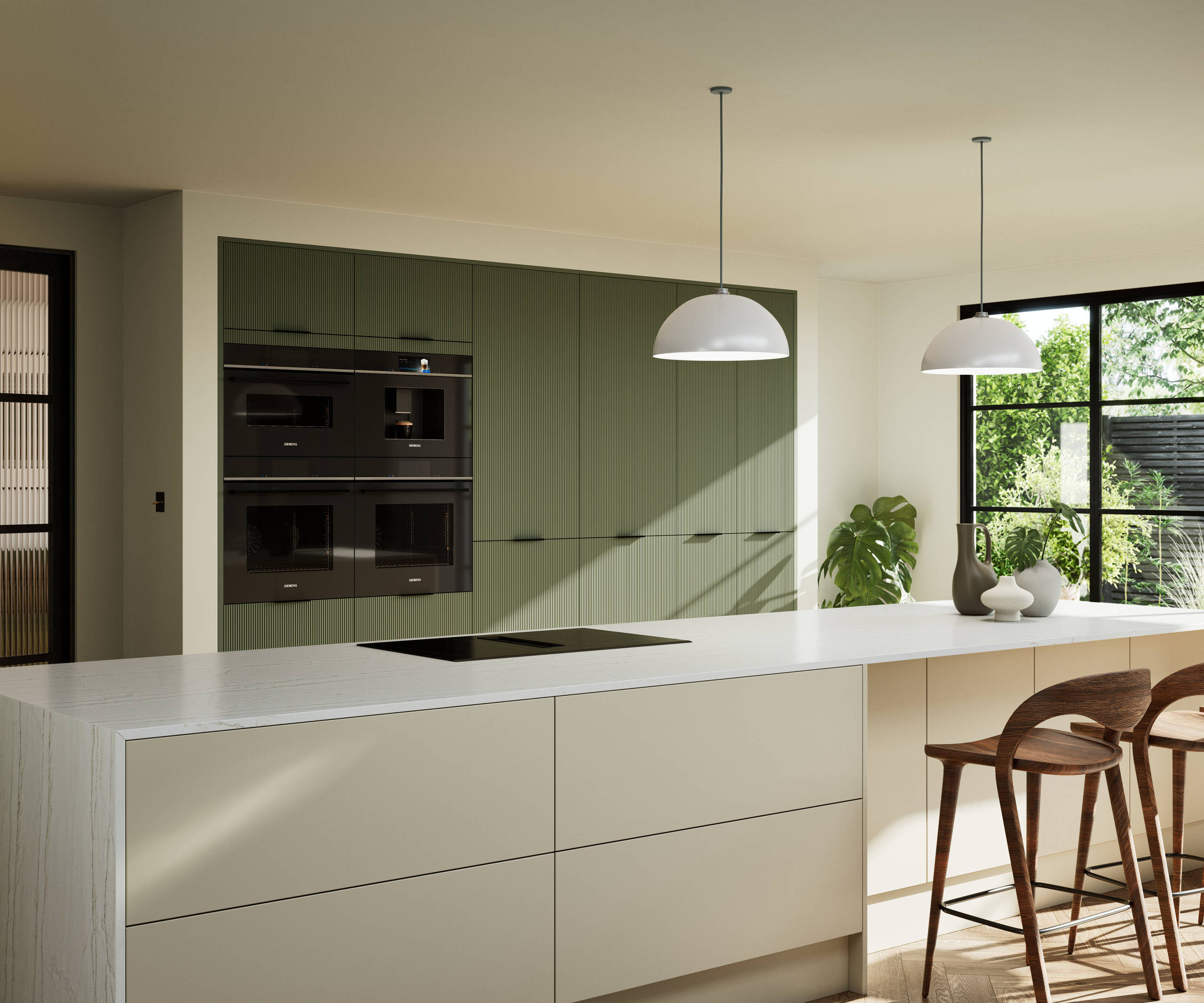 Green fluted kitchen fronts on tall cabinets with built-in appliances and black handles, light neutral shade kitchen island with white worktop and wooden barstools.