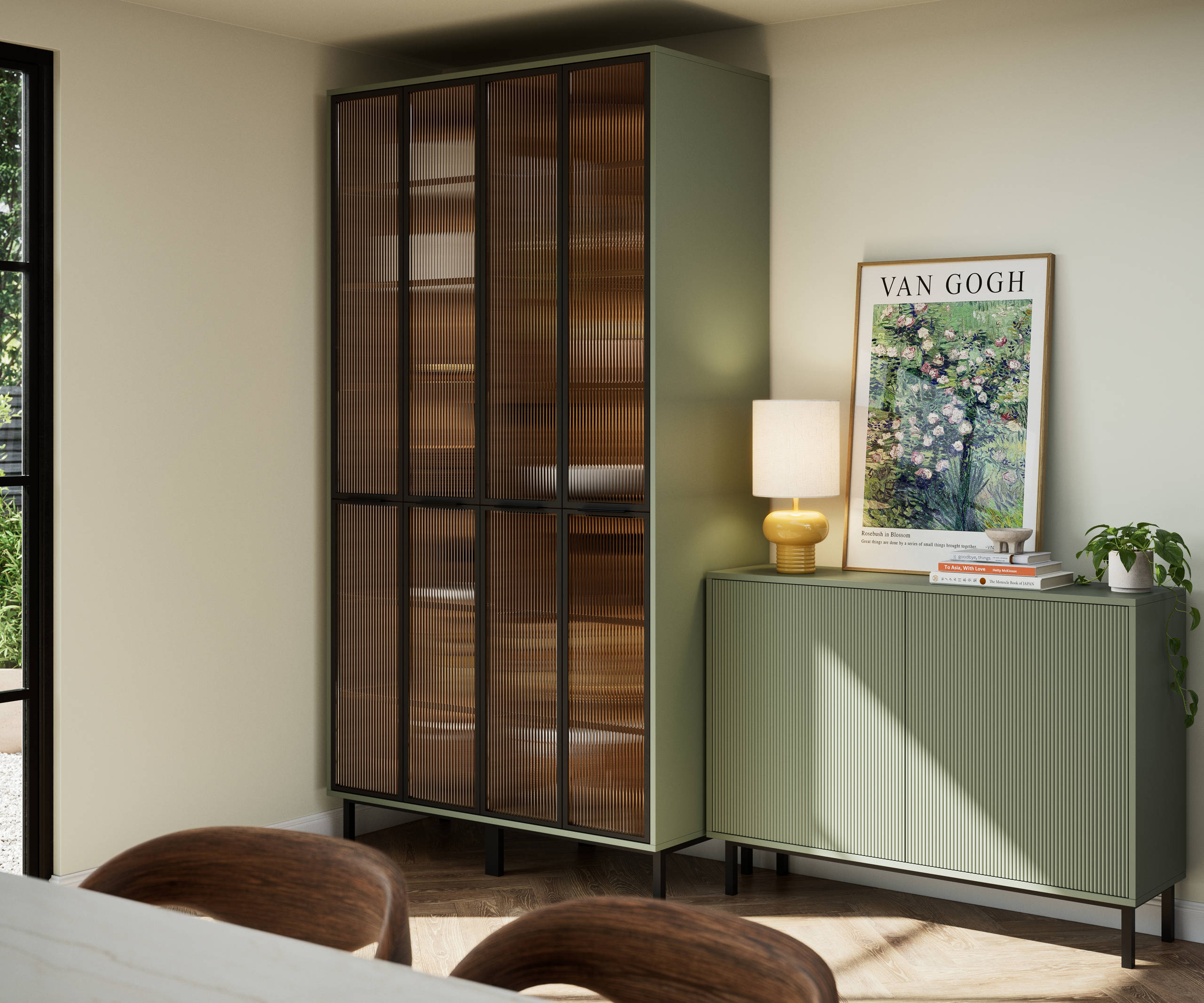 Vitrine with fluted glass in black metal frames, on green cabinet next to green fluted kitchen fronts on sideboard cabinets on black metal legs.