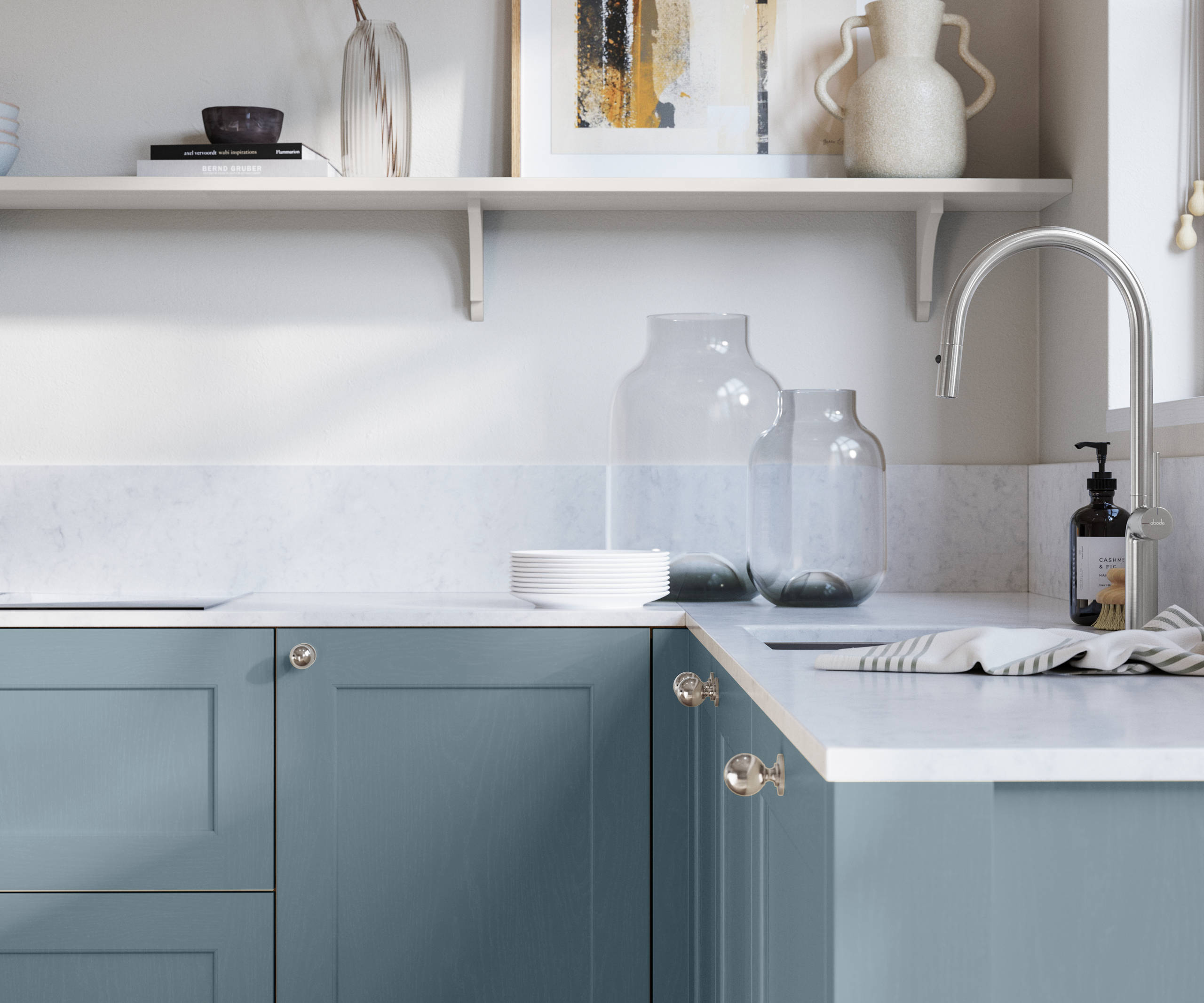 Ludlow, a traditional Shaker-style premium feel kitchen range with a visible woodgrain on its panelled doors here shown in the shade Portland Blue styled with steel knobs, steel tap, a white marbled worktop with matching splashback.