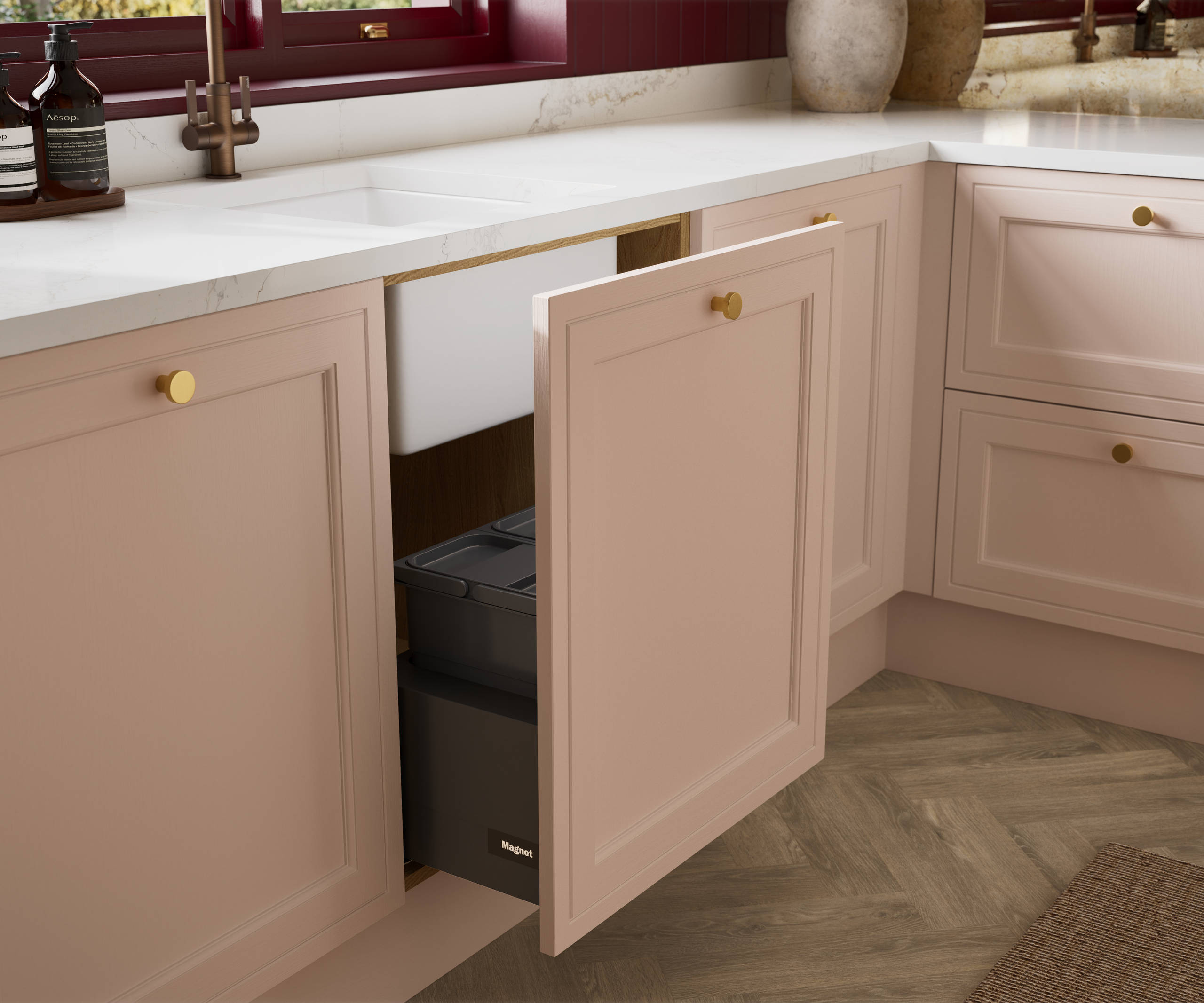 Opened sink drawer in painted wood grain Shaker style Bewdley kitchen with cabinets in light pink shade Chalk Blush, marbled worktop and brass knobs.