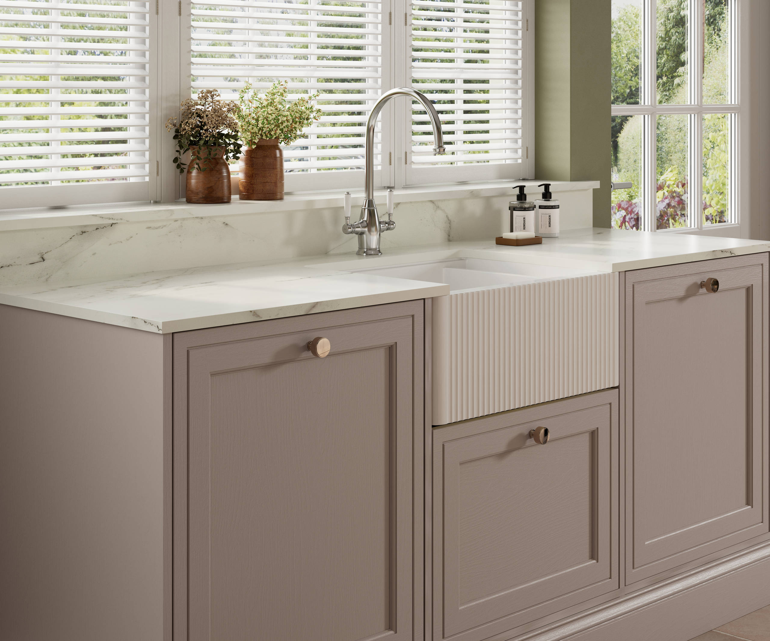 Shaker style painted wood grain cabinets Bewdley in the shade Cornish Clay with a marbled worktop and matching upstand, striped belfast sink with ceramic handle stainless steel tap.