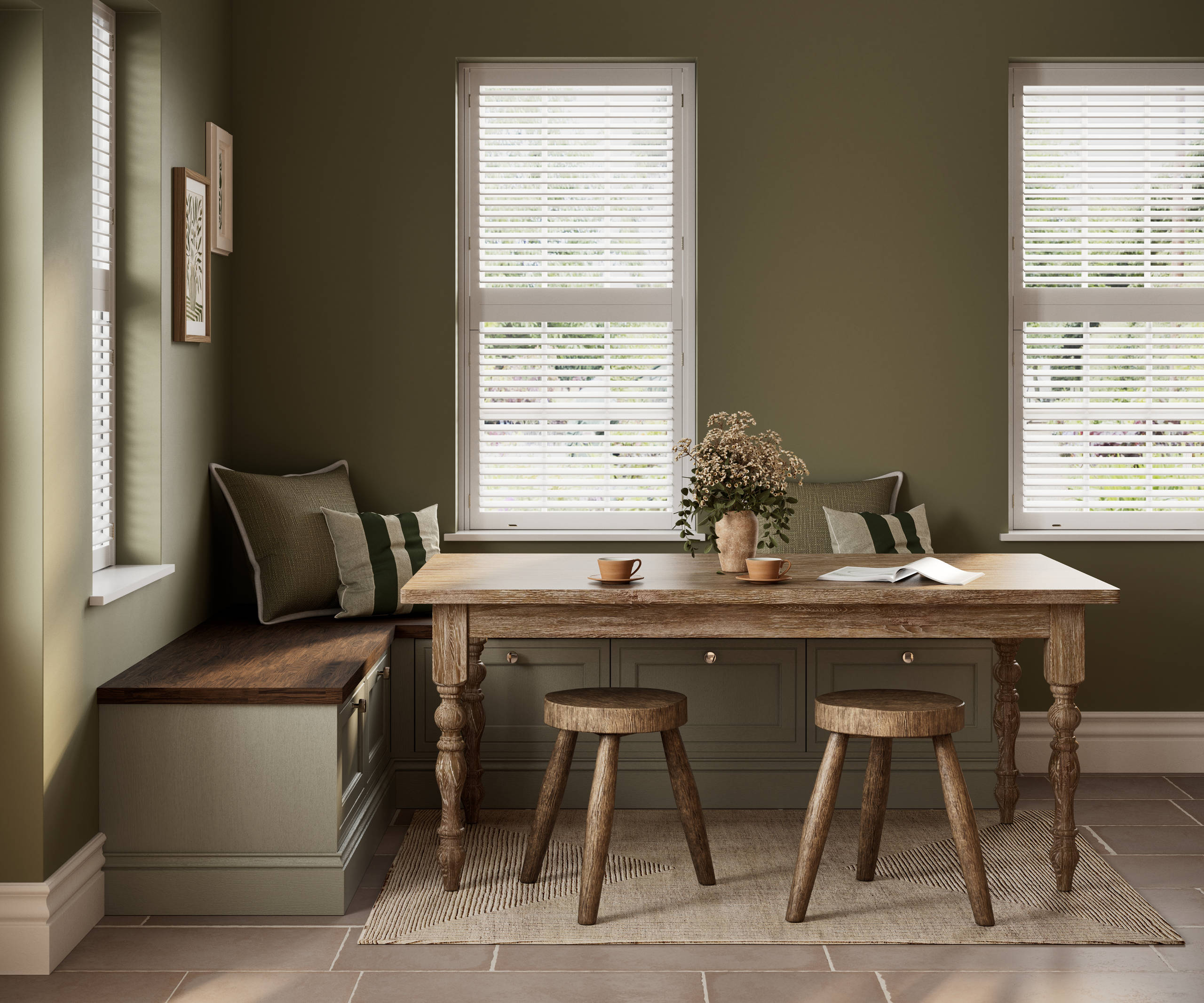 Dining area with low Shaker style painted wood grain cabinets Bewdley cabinets as a bench with a wooden table and stools in a room with painted green walls.