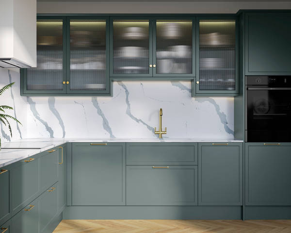 Modern Shaker kitchen Brunswick Spruce, a muted green shade, wall cabinets with fluted glass doors, Quartz Bianco Calacatta worktop and splashback, brass accessories like knobs, handles and tap, and a light wood herringbone floor.