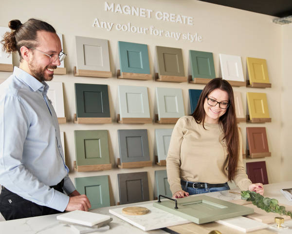 Kitchen designer showing samples of fronts, worktops and handles to a woman in a Magnet Showroom.