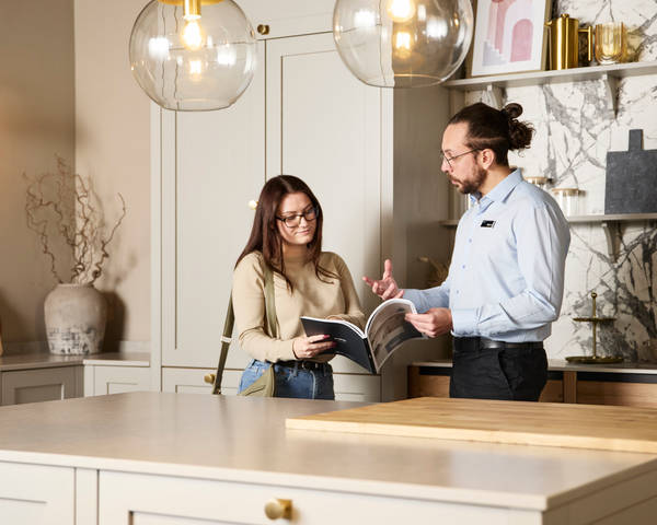 Woman and kitchen designer looking at and discussing a brochure in Shaker style kitchen at a Magnet Showroom.