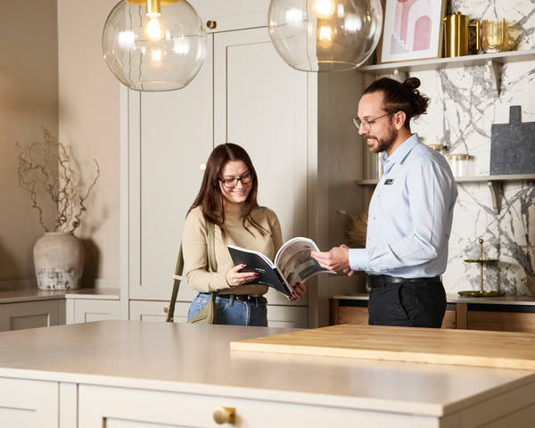 Woman and kitchen designer looking at and discussing a brochure in Shaker style kitchen at a Magnet Showroom.