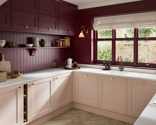 Painted wood grain Shaker style Bewdley kitchen with cabinets in light pink shade Chalk Blush, marbled worktop, brass knobs, red Morello wall-mounted cabinets with matching shelves and wall panel, built- in wine storage.