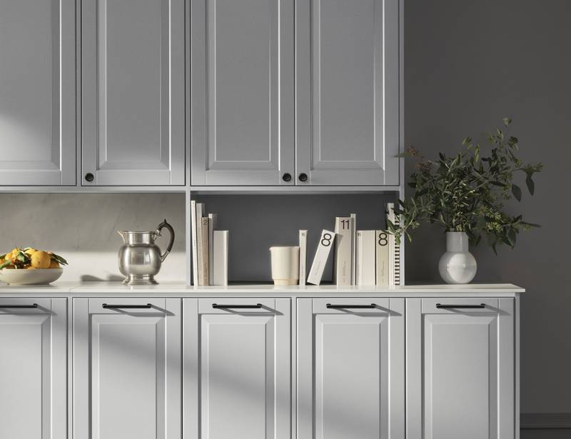 Lys grå landkøkken Nordic Sky fra INVITA med fyldningslåger, sort håndtag, vitrineskab med sprosselåger og hvid marmor laminatbordplade