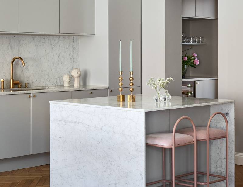 Lys grå Athena Sky køkken fra INVITA, køkkenø med dekorativ side og bordplade i lys grå marmor, håndtag, vandhane og lysestager i messing