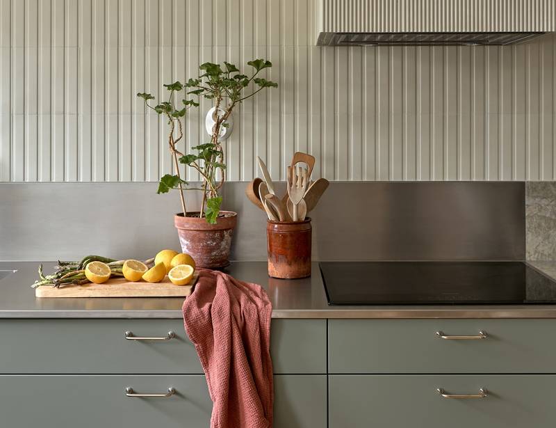 Lys grågrøn Athena Salvie køkken fra INVITA, håndtag och bordplade med splashback i rustfritt stål