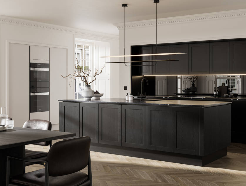 Handleless frame doors Integra Wardley Sumi black kitchen with kitchen island, Integra Soho Limestone tall cabinets with integrated ovens, black dining table and chairs, pale oak chevron flooring.