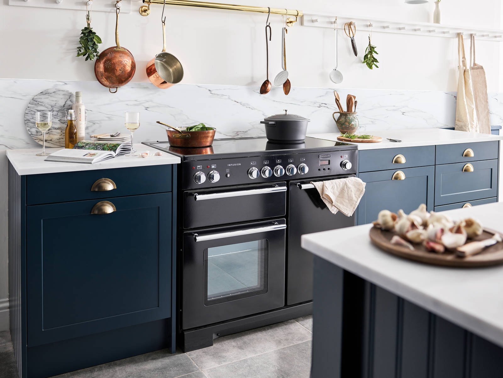 Dunham voyage kitchen with white marbled worktop and backsplash, and a black range cooker