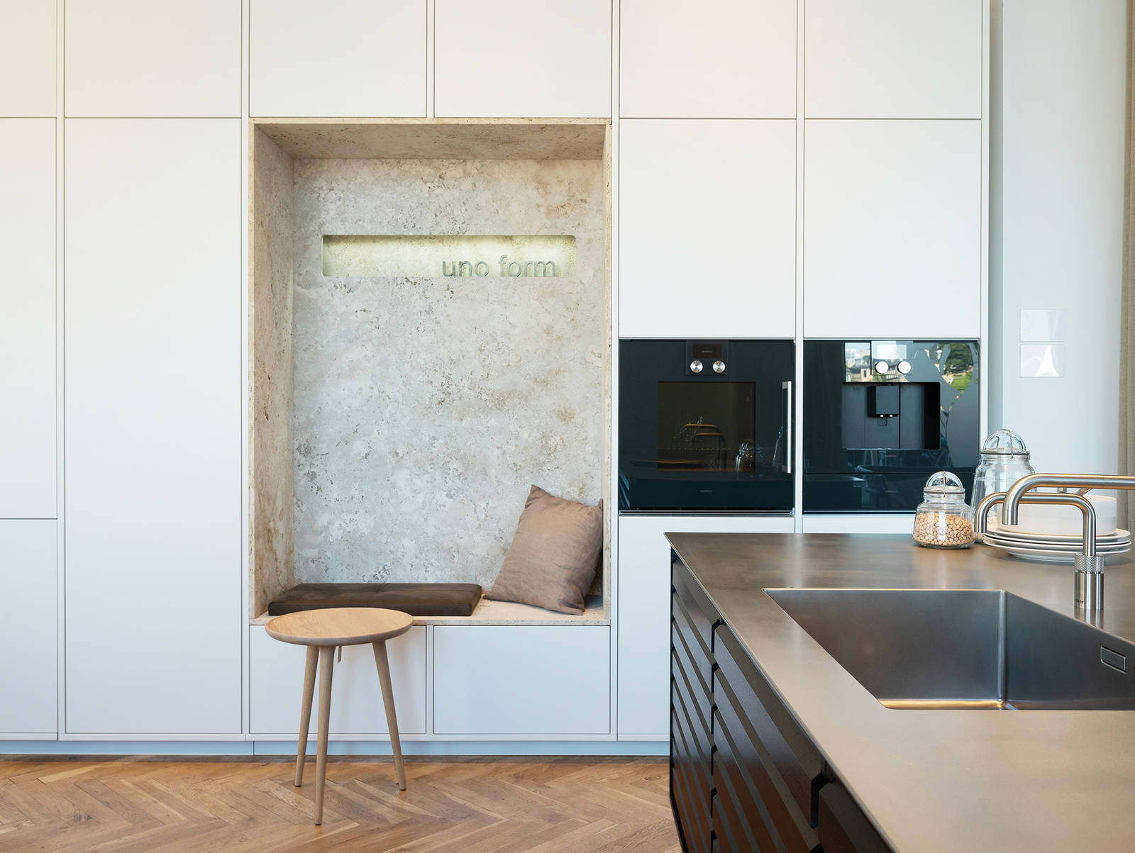 Køkkenø i røget eg med stålbordplade og hvid højskabsvæg med alkove