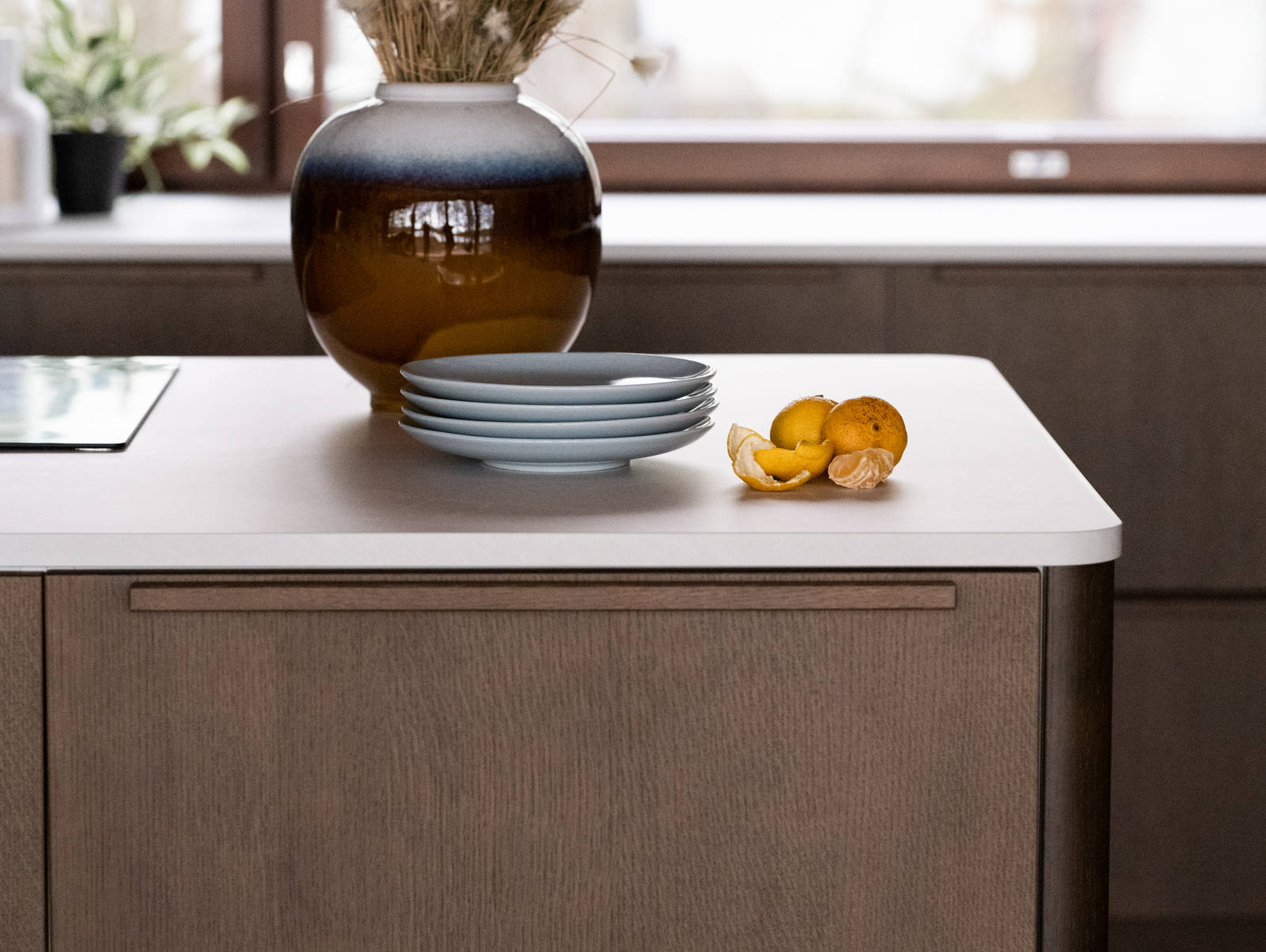 Laminaatin ja tammiviilun pyöristetyt reunat keittiösaarekkeessa, kukkalaukku työtasolla