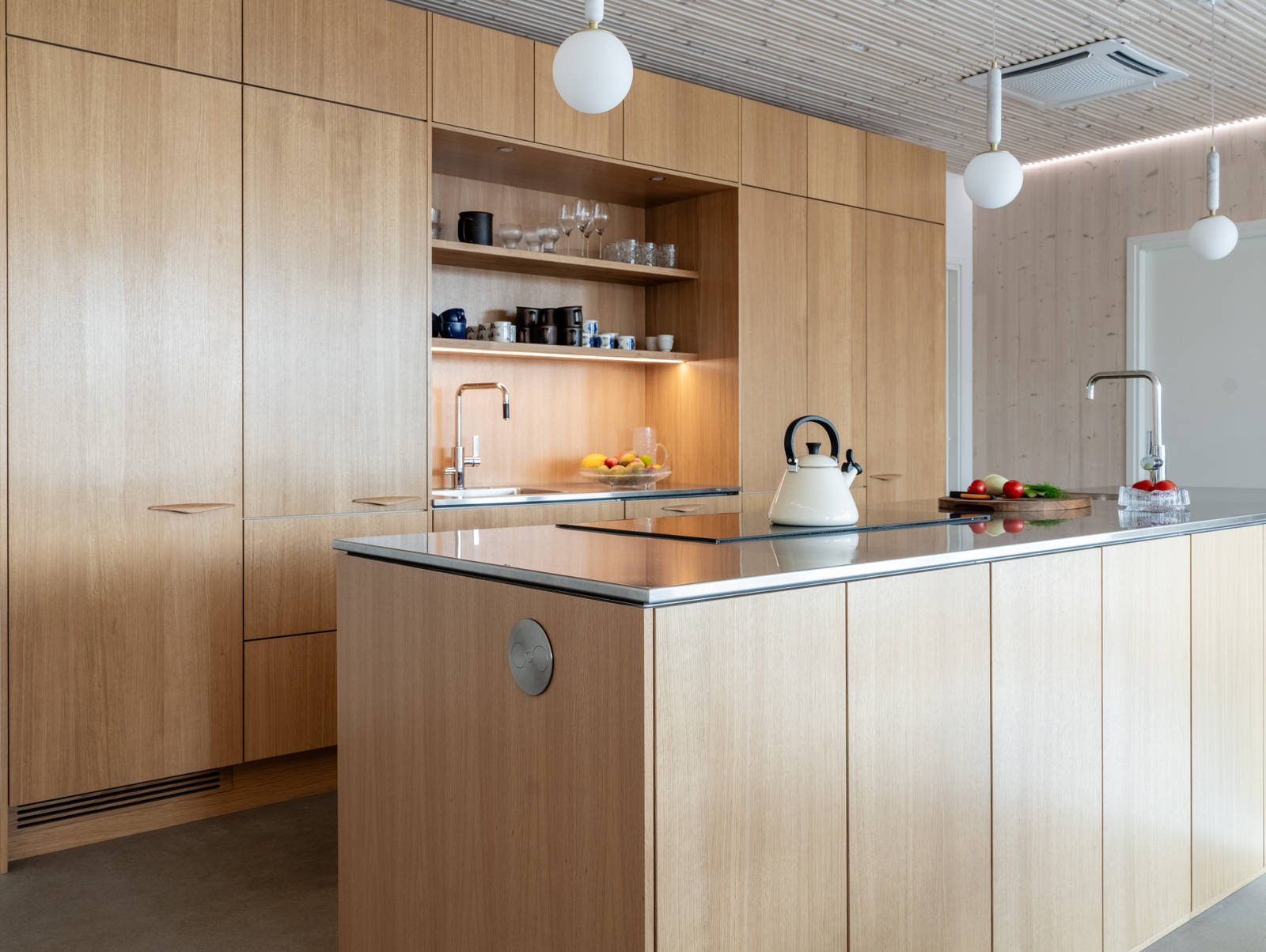 Aitoa luonnontammea Novartilta, yhdistelmä yhteensopivia puisia ja painonappikahvoja, keittiösaareke hanalla, tiskiallas ja ruostumattomasta teräksestä valmistettu työtaso.