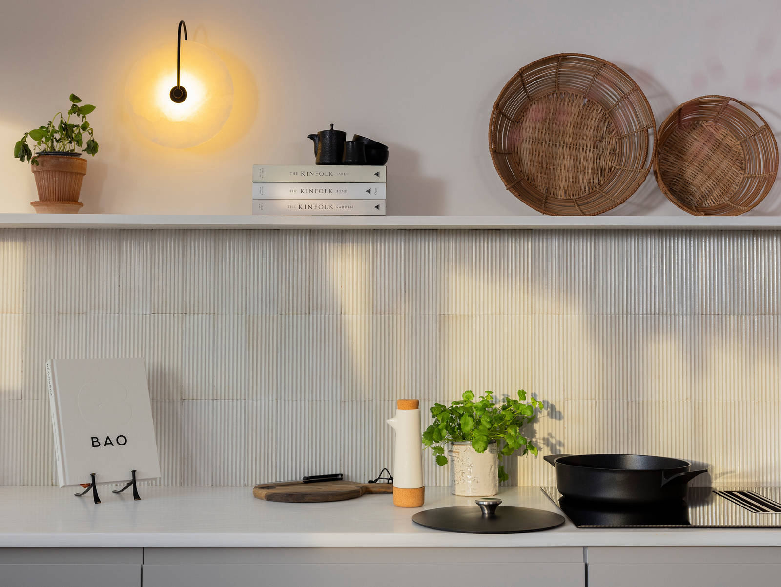 Countertop of Yasmin Wyatts matt finish Luna kitchen from Magnet, splashback and wall shelf, a black skillet pan on the AEG built-in FlexiBridge Hob with Extractor