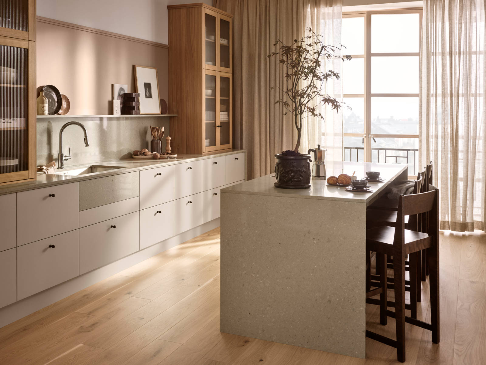 Köksö i beige köket Arkitekt plus gryning från Marbodal, med bardisk i köksön, belfast diskho, vitrinskåp med träram i ek och räfflat glas ovanpå köksbänken