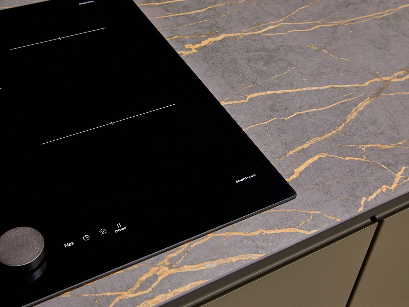 An organic marble-effect kitchen worktop, shown with modern Duxbury kitchen cabinets in Fawn, and black glass hob from SmartThings.