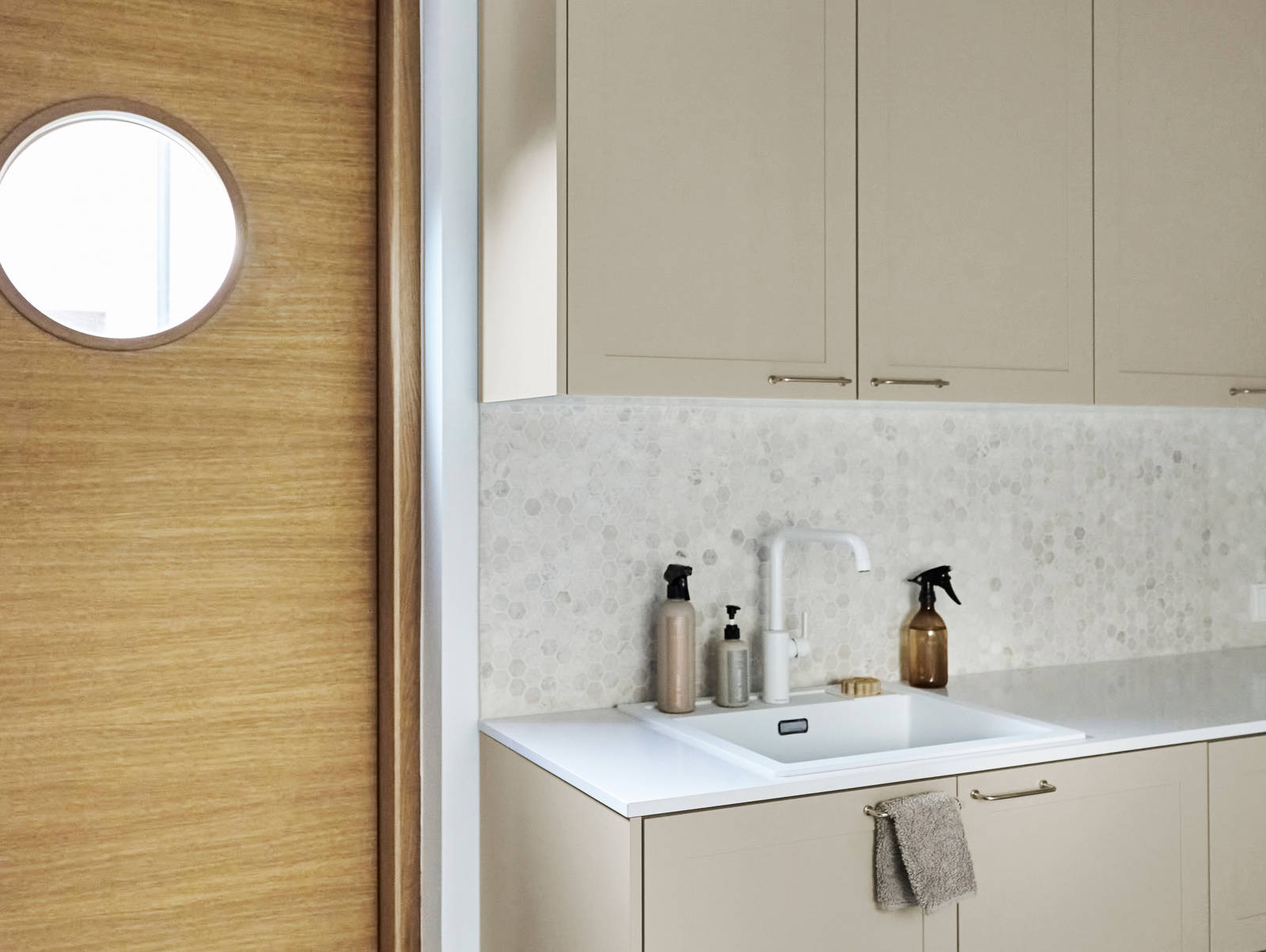 Beige-kaapit Novartilta ja harmaa marmorinen työtaso kodinhoitohuoneessa