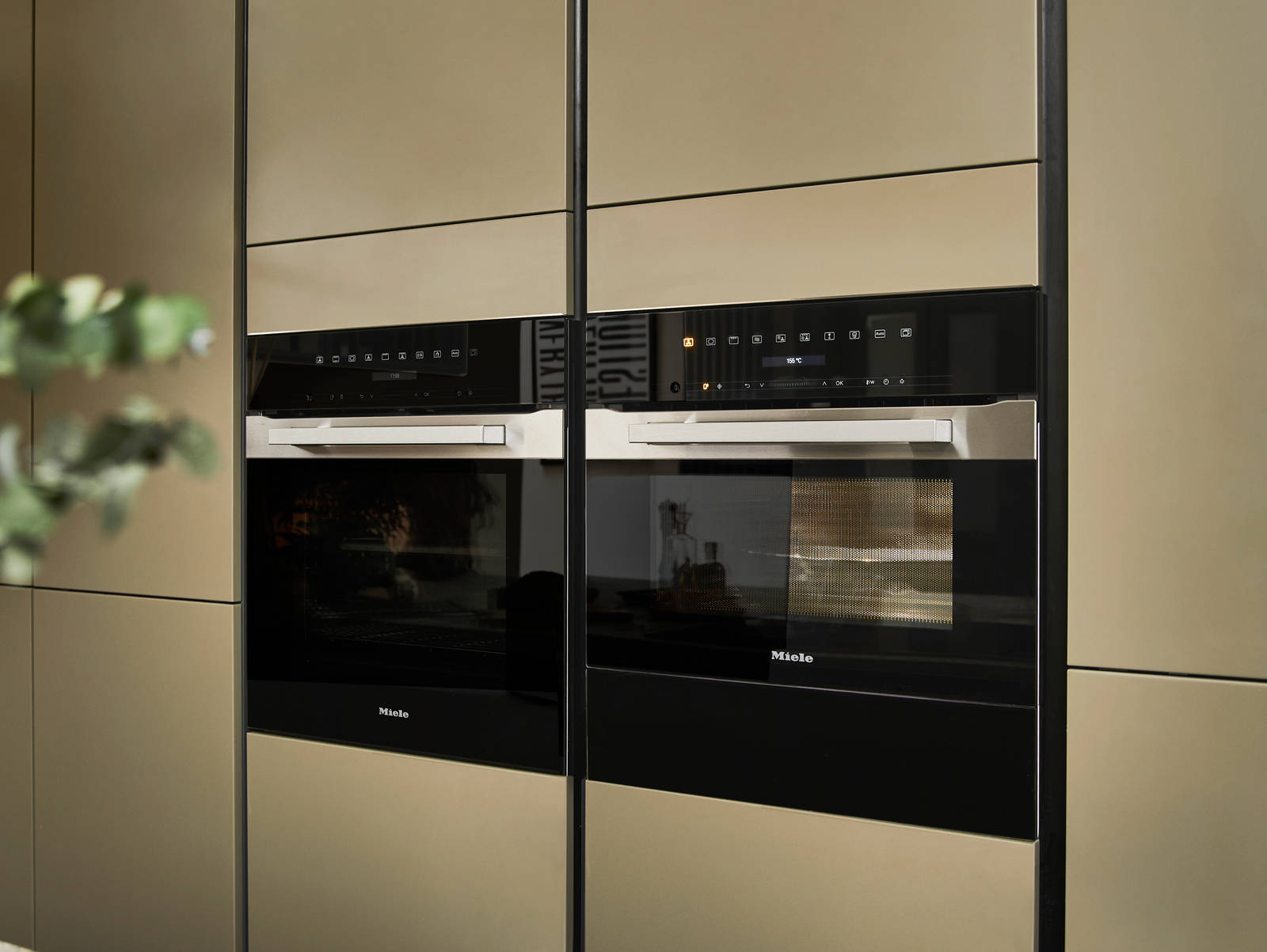 Built-in Ovens in modern slab front Balmoral Soho cabinetry from Magnet, Dekton in Ceppo worktop of kitchen island in foreground.