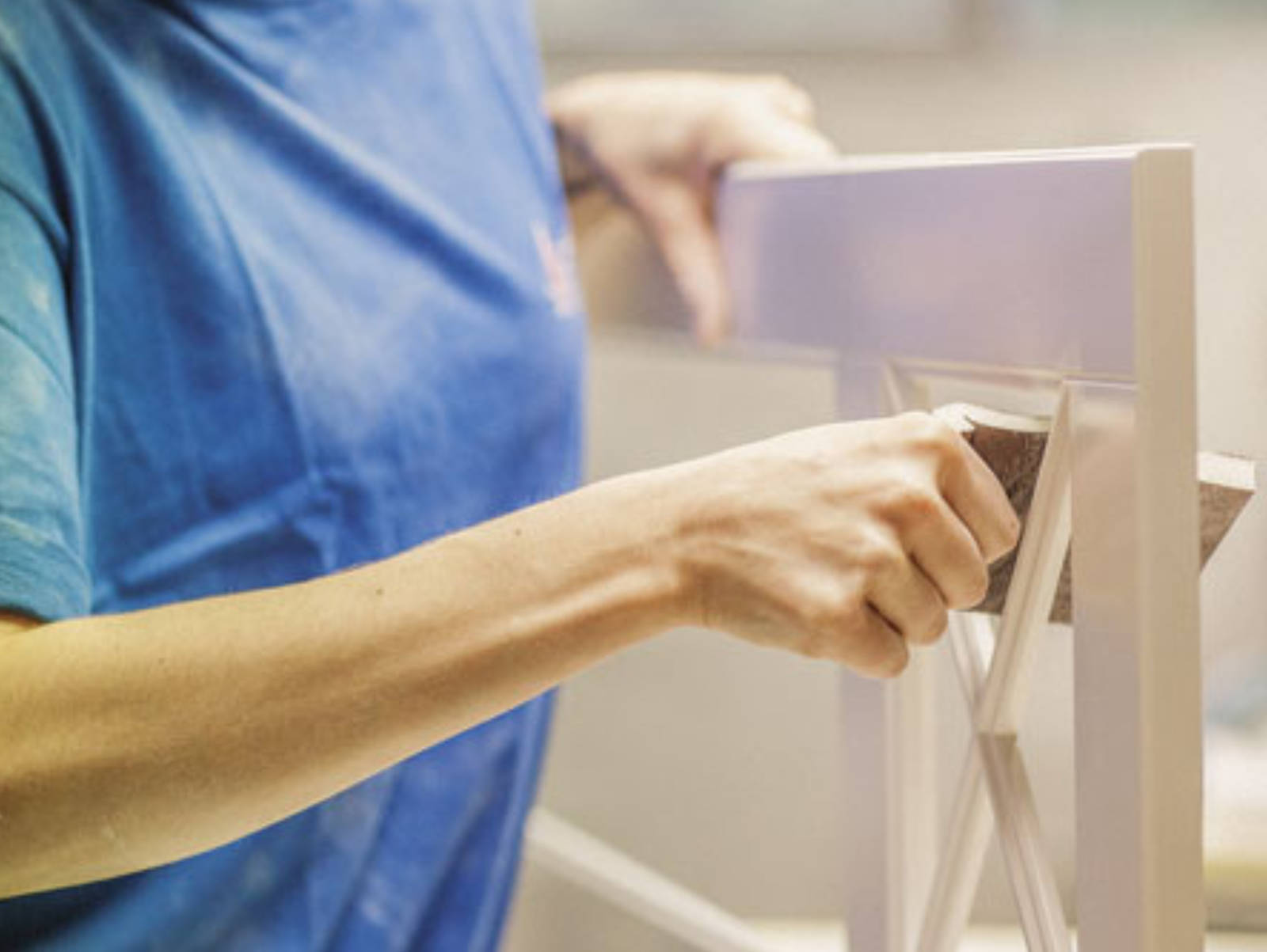 Nærbillede af nogen, der sliber en vitrineskabsdør